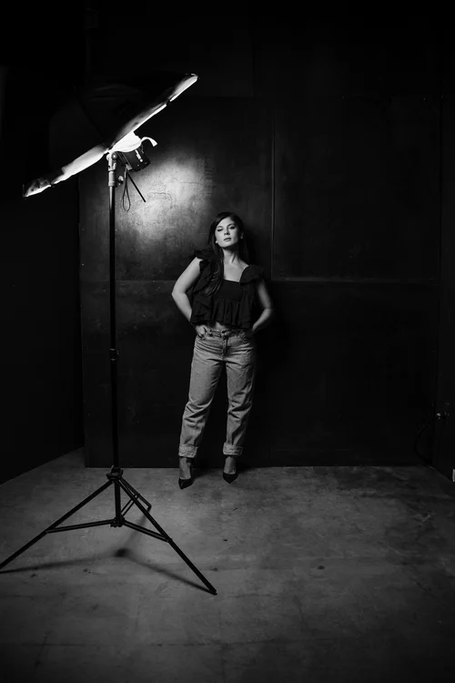 Black and white behind the scenes shot of a full length portrait lit with a single monolight