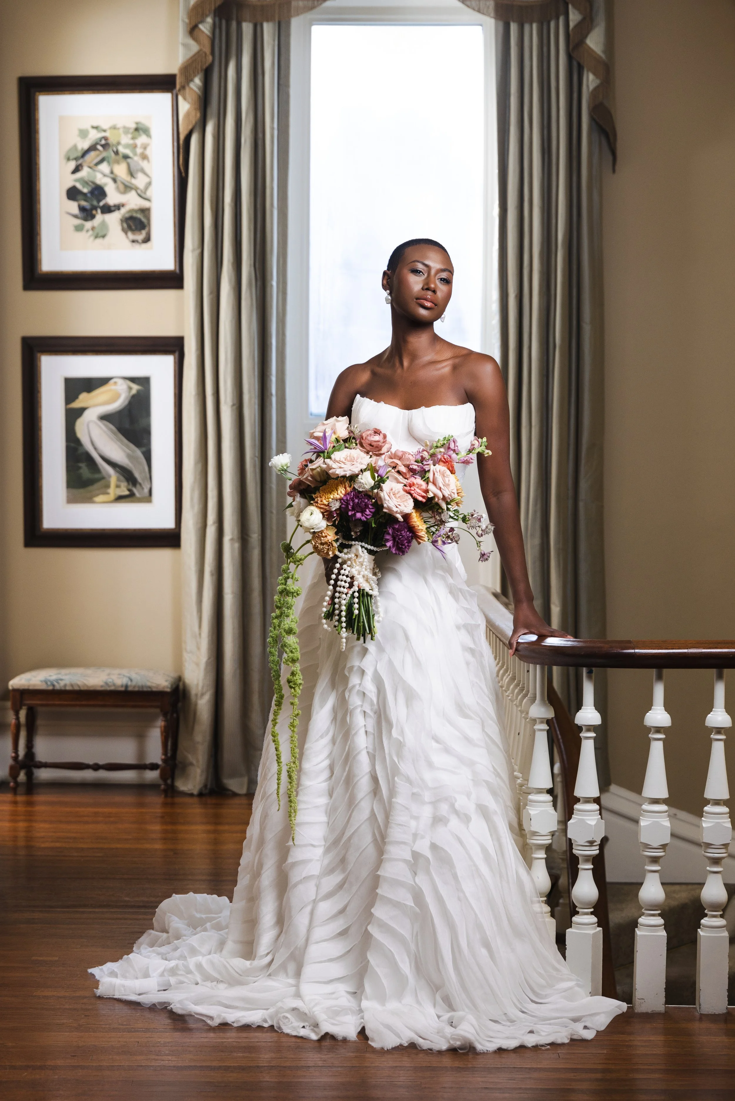 Bride in minimalist halter gown poses on staircase landing, framed by soft natural light and classic architecture in luxury bridal editorial at Watson House