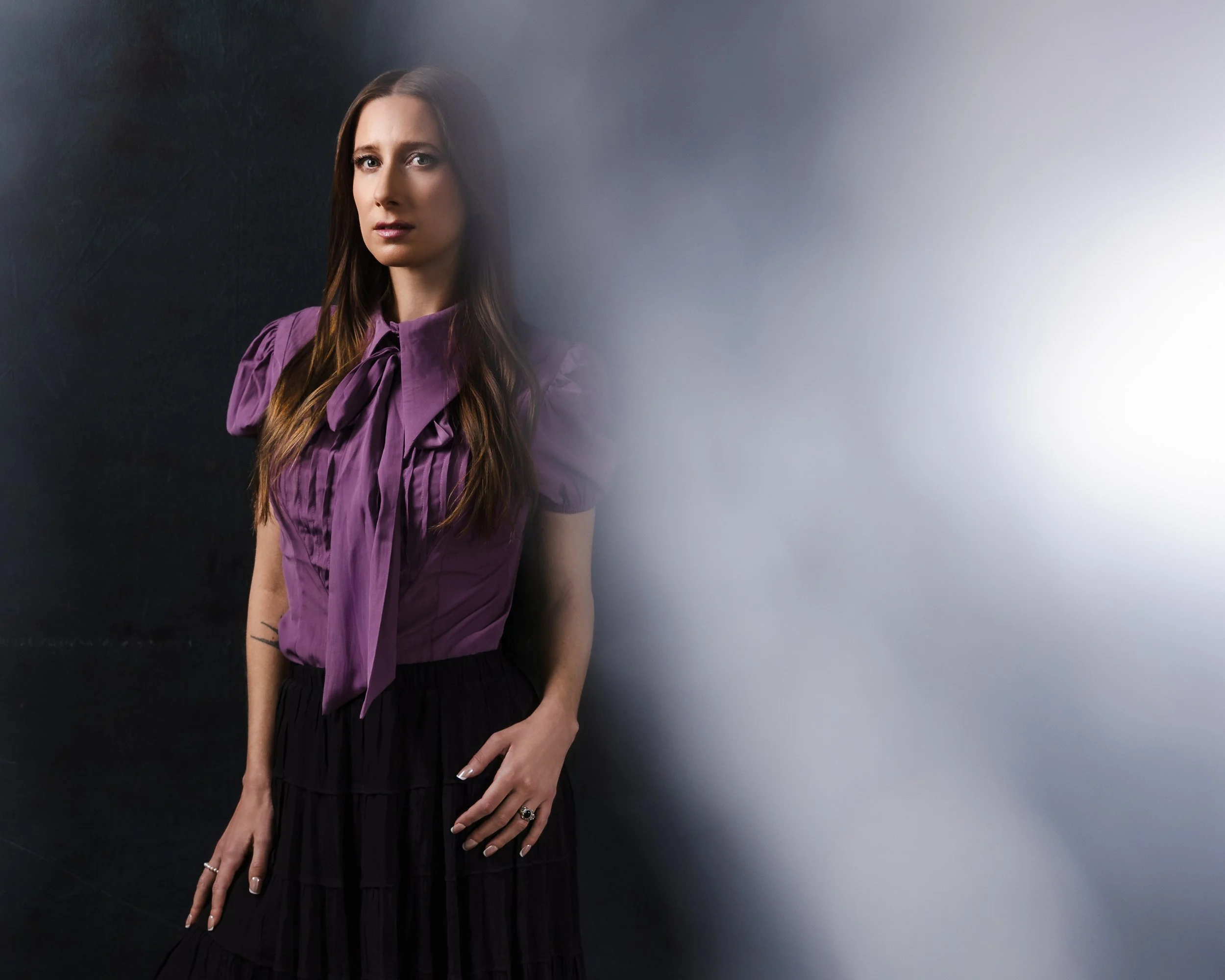 Three-quarter studio portrait of Lauren River with bubble wrap diffusion creating soft edge glow and misty texture over a hand-painted canvas backdrop.