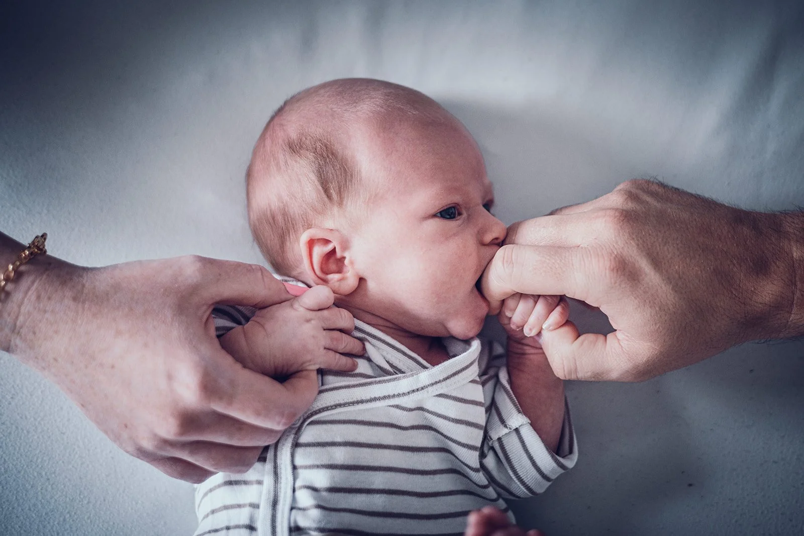 Neugeborenes Baby in den Armen seiner Eltern bei einem natürlichen Newbornshooting in München