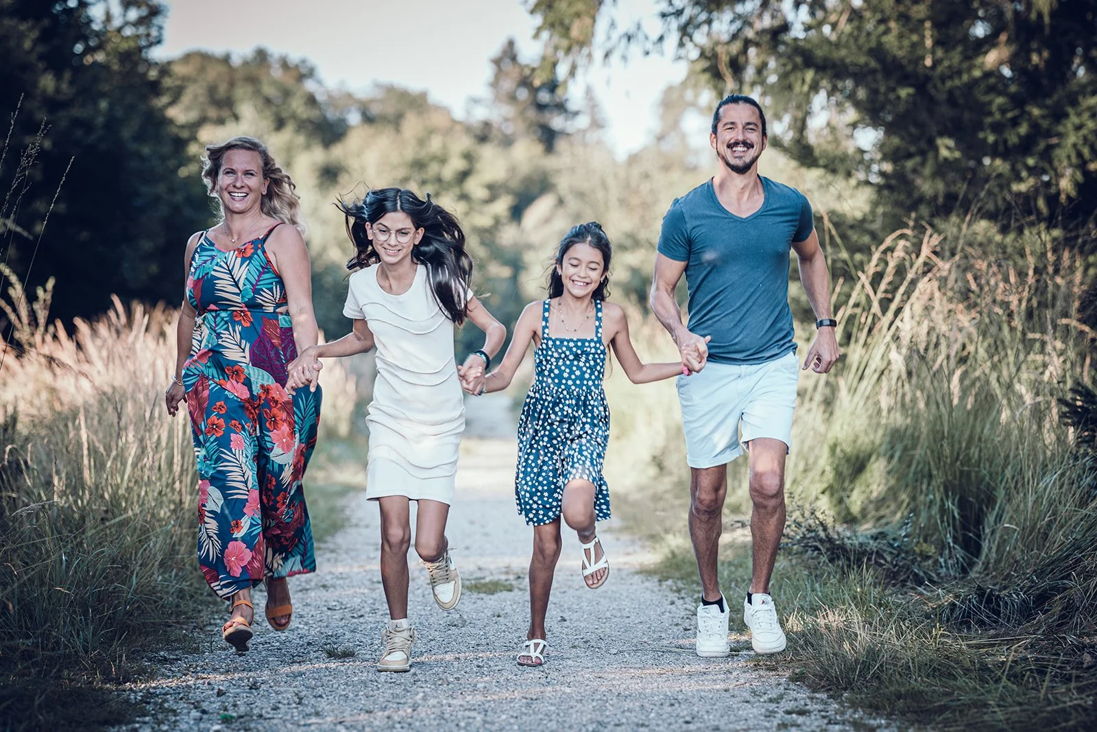 Familie läuft gemeinsam über einen Weg – natürliche Familienfotografie in München