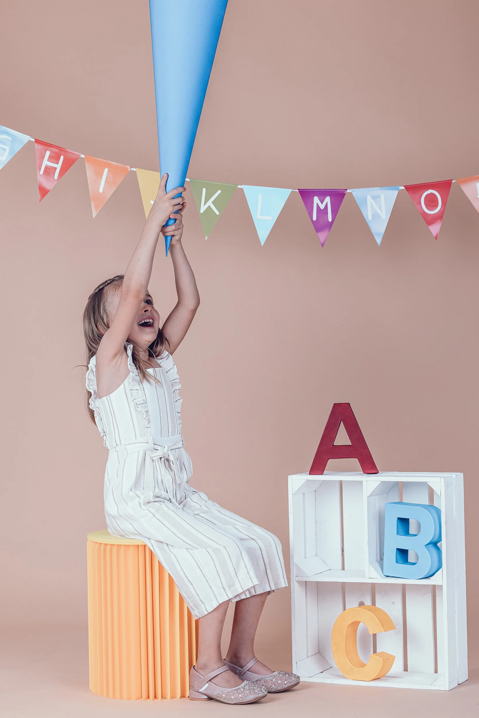 lachendes Mädchen mit großer blauer Schultüte beim Einschulungsshooting im Fotostudio in München.