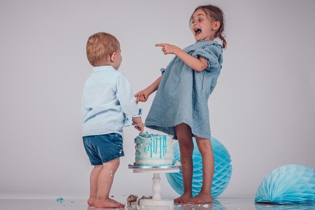 Cakesmash-Shooting im Studio – zwei Kinder stehen lachend vor einer Geburtstagstorte
