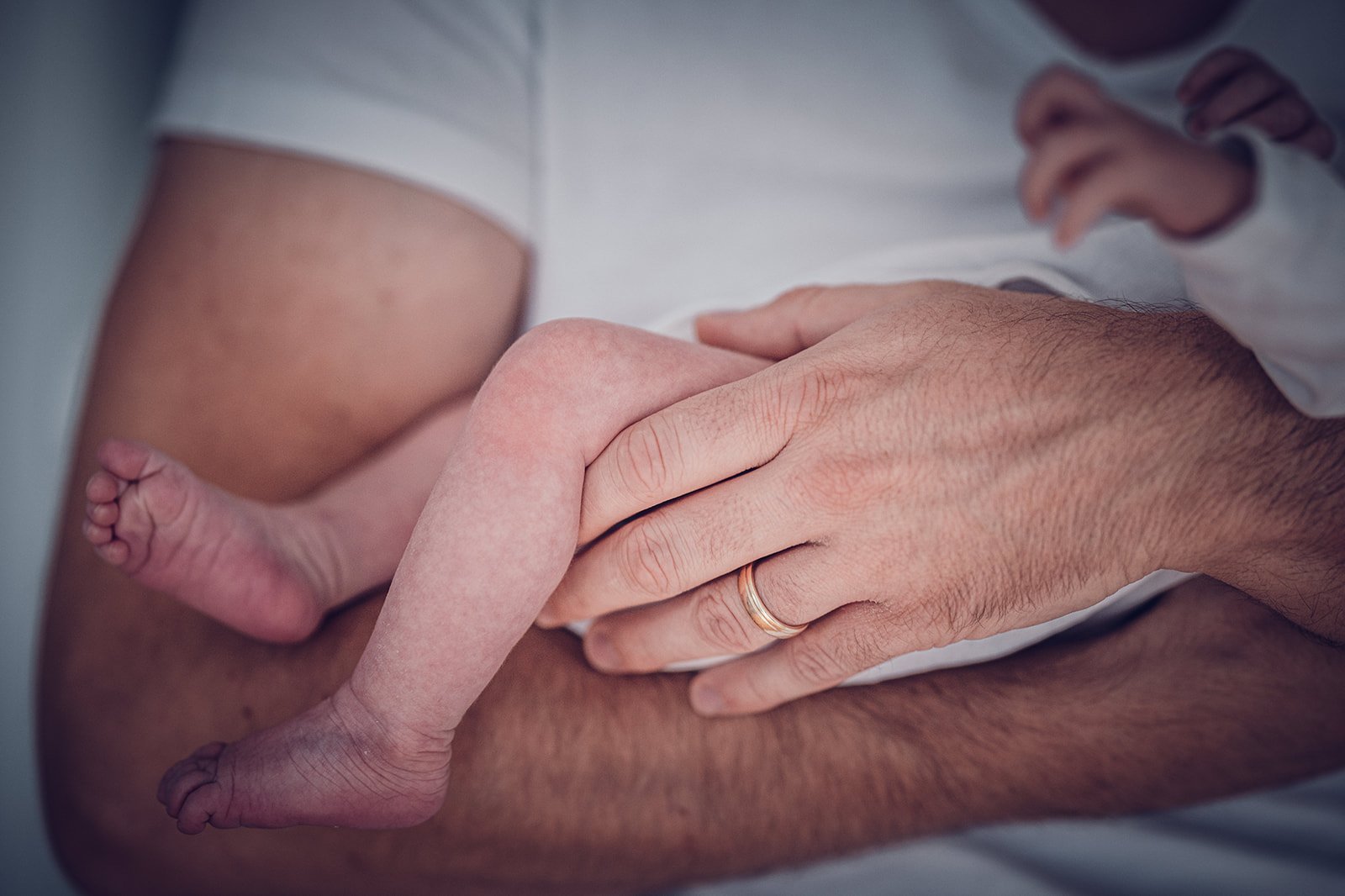 Newbornfotografie – Detailaufnahme von Babyfüßen in den Händen der Eltern