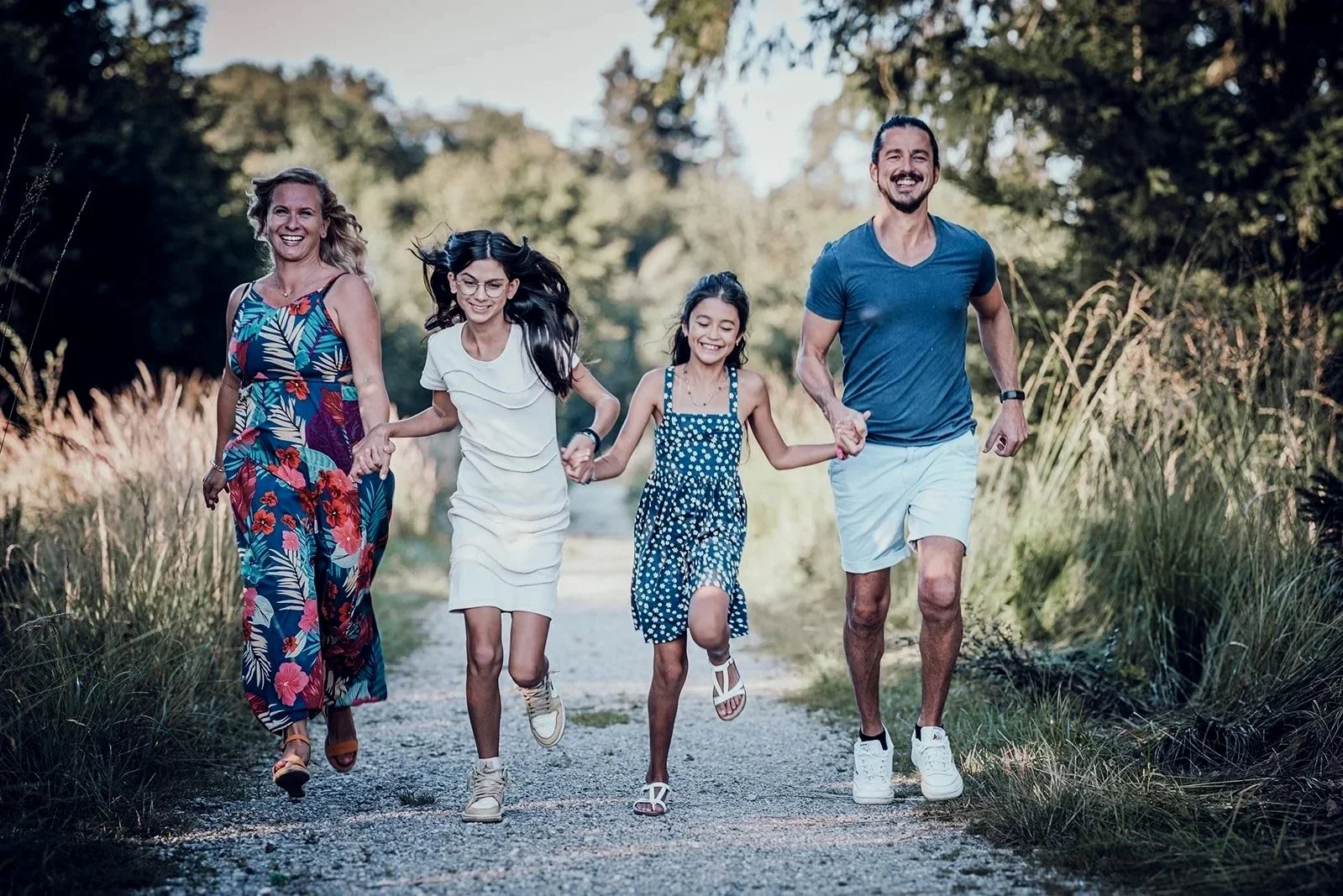 Familienfotografie im Freien – Familie läuft gemeinsam über einen Waldweg