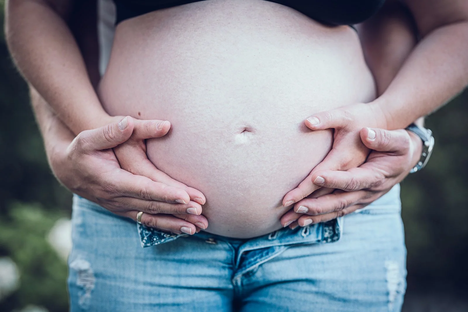 Babybauch Fotografie im Studio – Hände halten den runden Bauch, natürliche Schwangerschaftsfotografie in München
