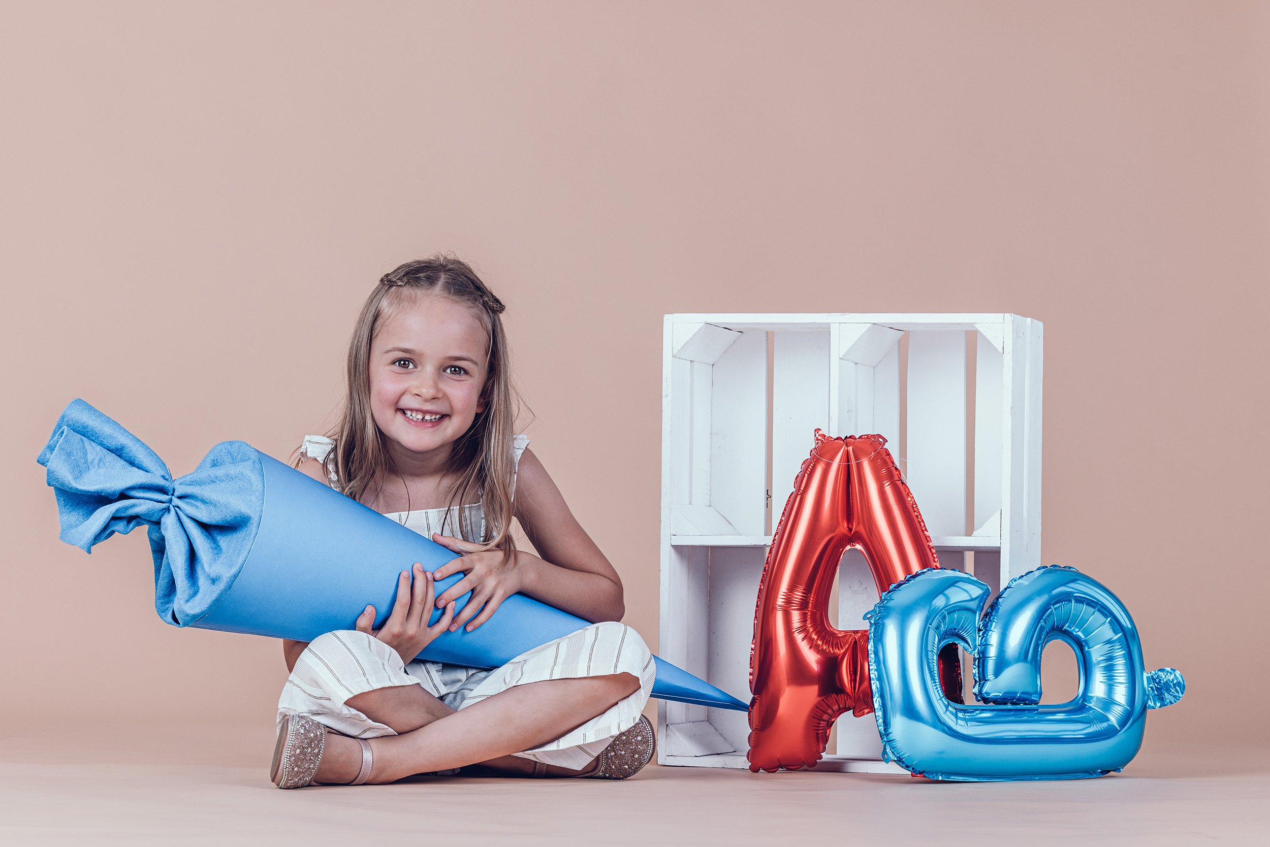 stolzes Mädchen mit großer blauer Schultüte beim Einschulungsshooting im Fotostudio in München.