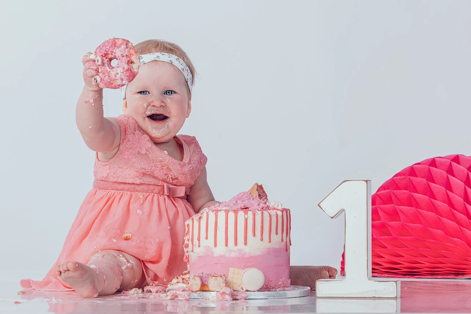 Cakesmash-Shooting im Studio – ein Kleinkind sitzt lachend vor einer Geburtstagstorte