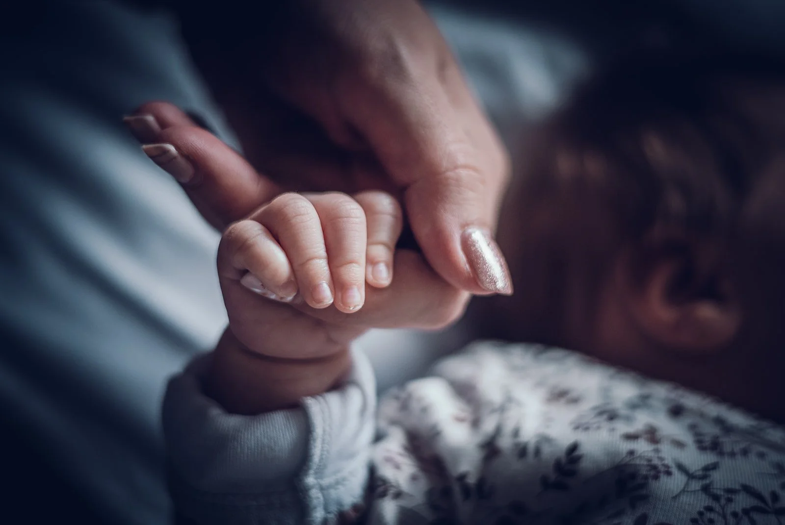 Zarte Babyhand umschließt den Finger von Mama – Newbornfotografie in München