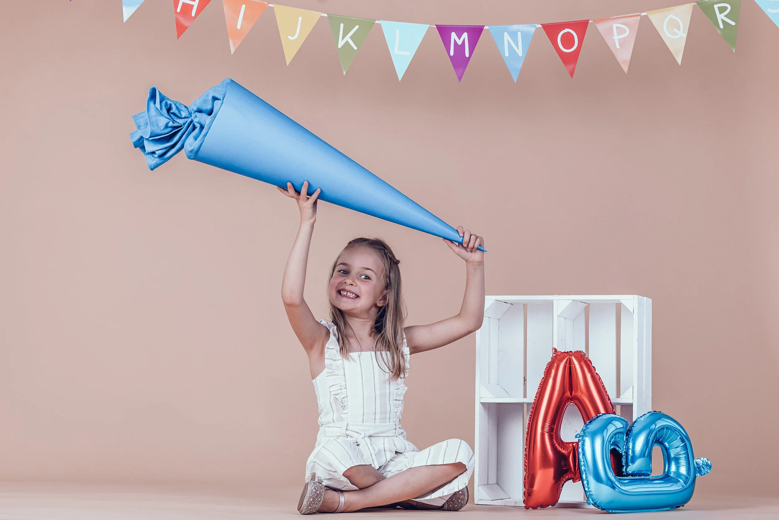 Mädchen mit großer blauer Schultüte beim Einschulungsshooting im Fotostudio in München.