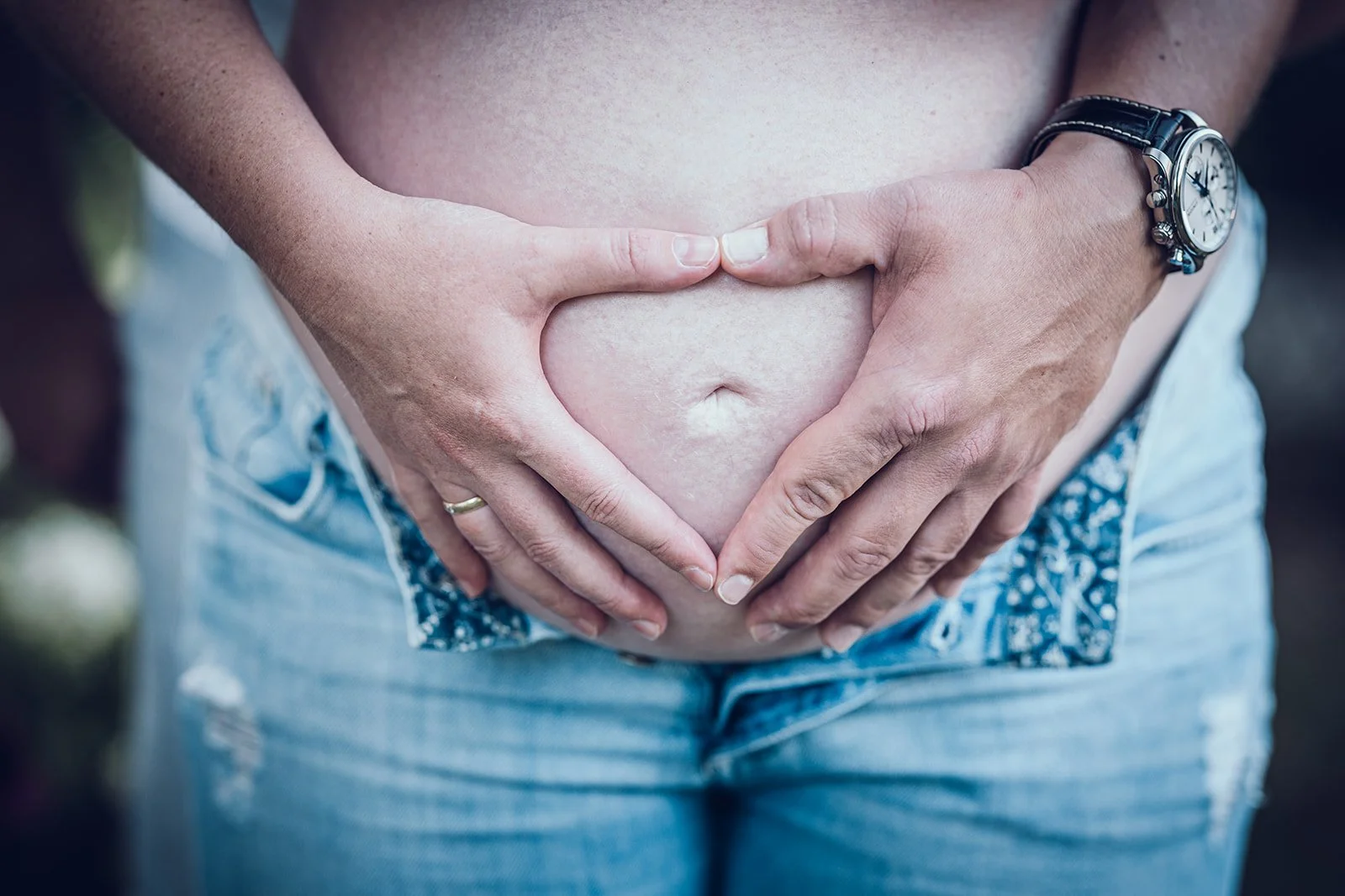 Babybauch Fotografie in der Natur – Hände halten den runden Bauch, natürliche Schwangerschaftsfotografie in München