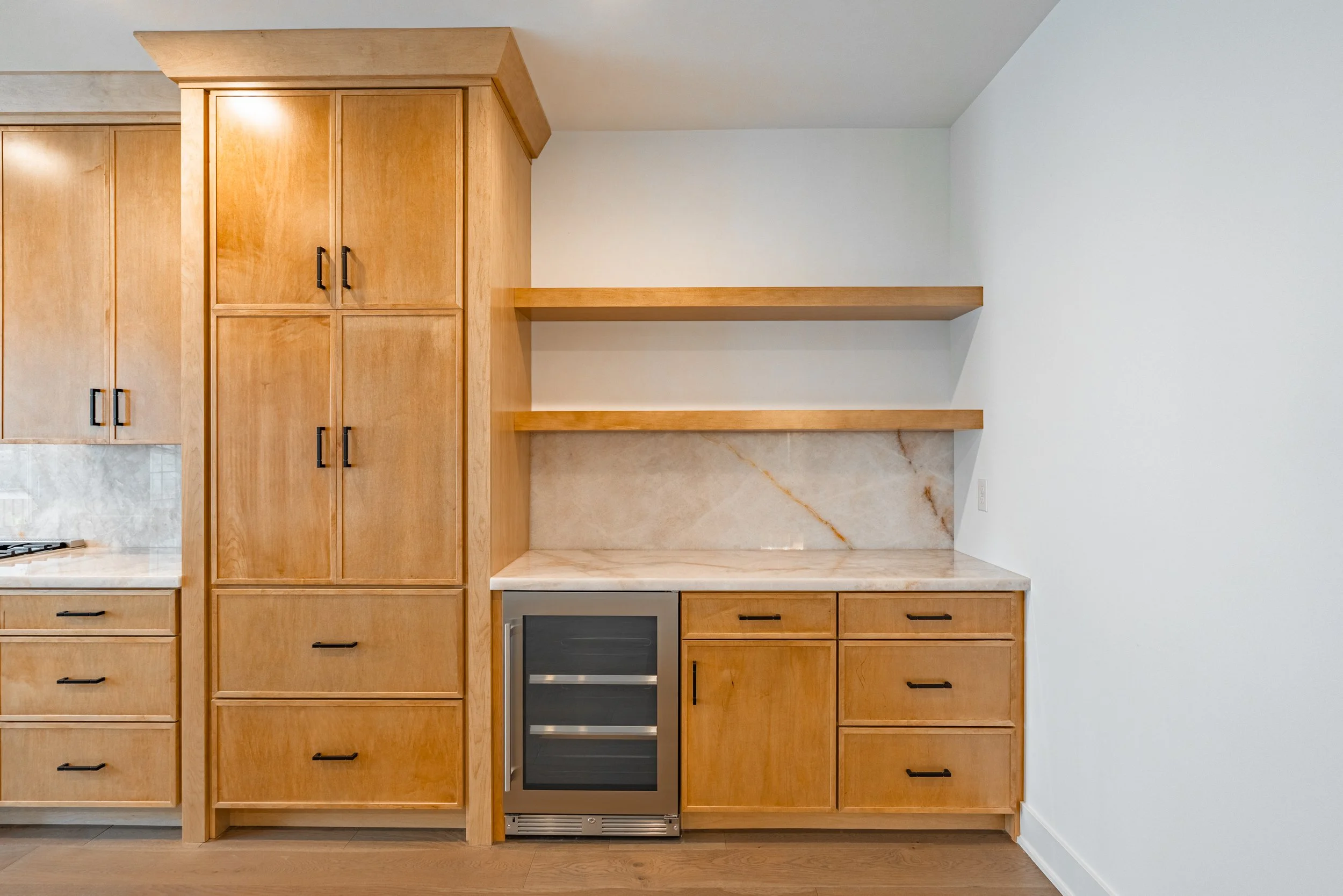 Kitchen with wooden cabinets, granite countertop, two open shelves, and a built-in wine cooler.