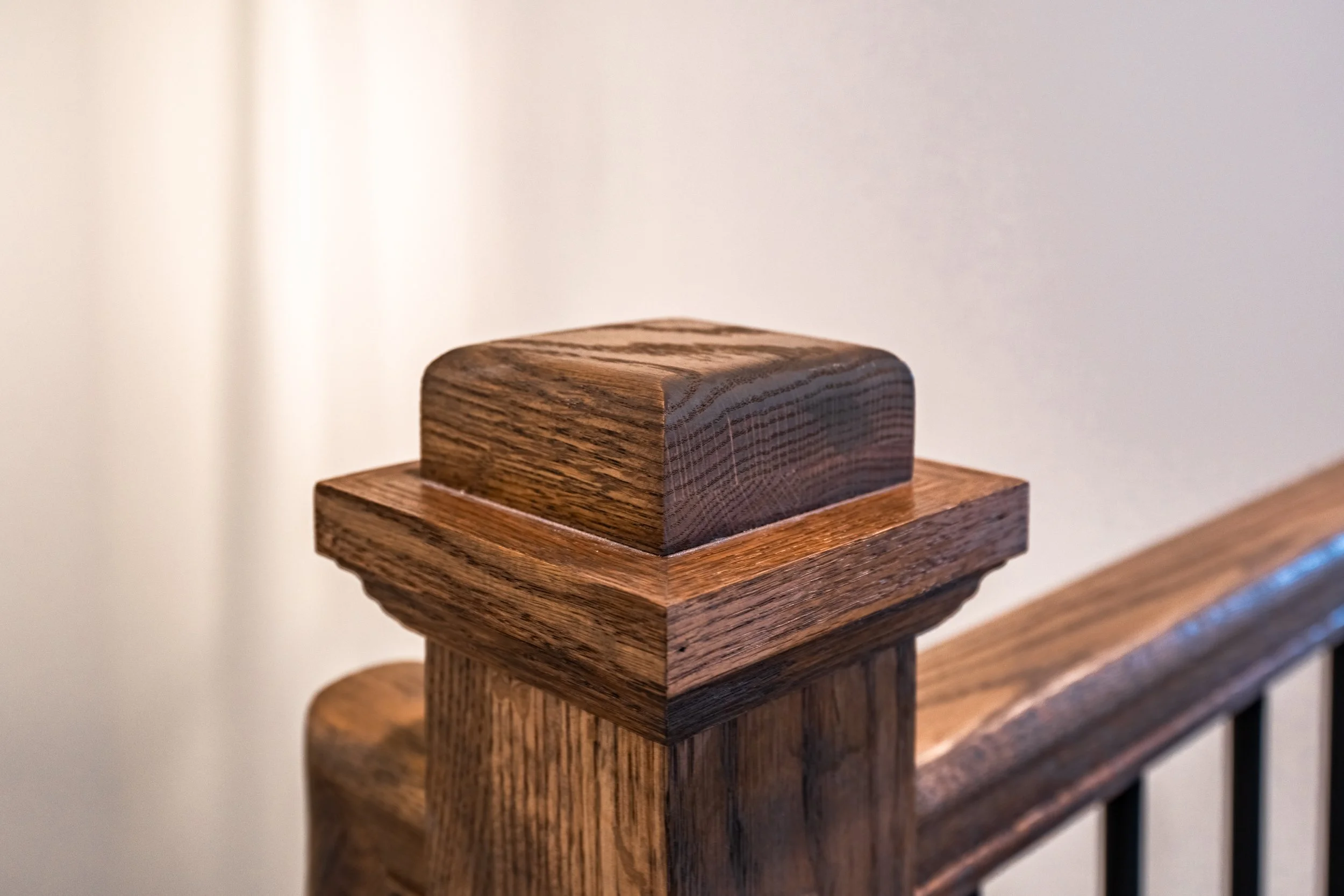 Close-up of a decorated wooden handrail on a staircase against a plain light-colored wall.