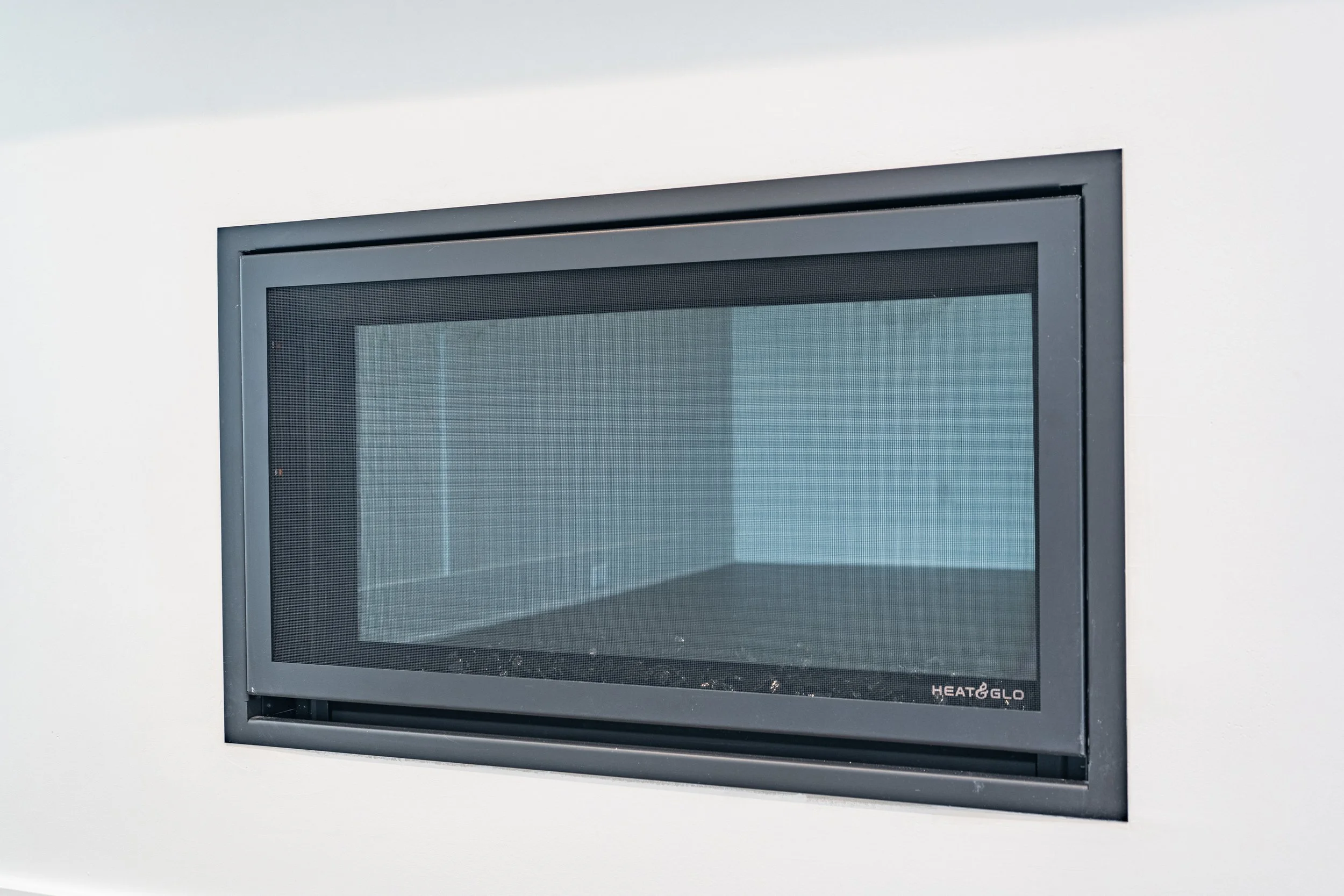 Close-up of a rectangular microwave oven with a black glass door and a black bezel, set against a white wall.