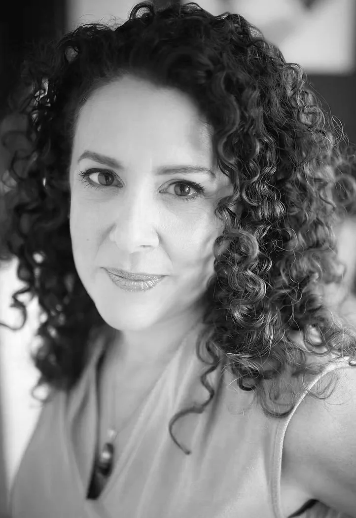 Black and white portrait of a woman with curly hair and a slight smile.