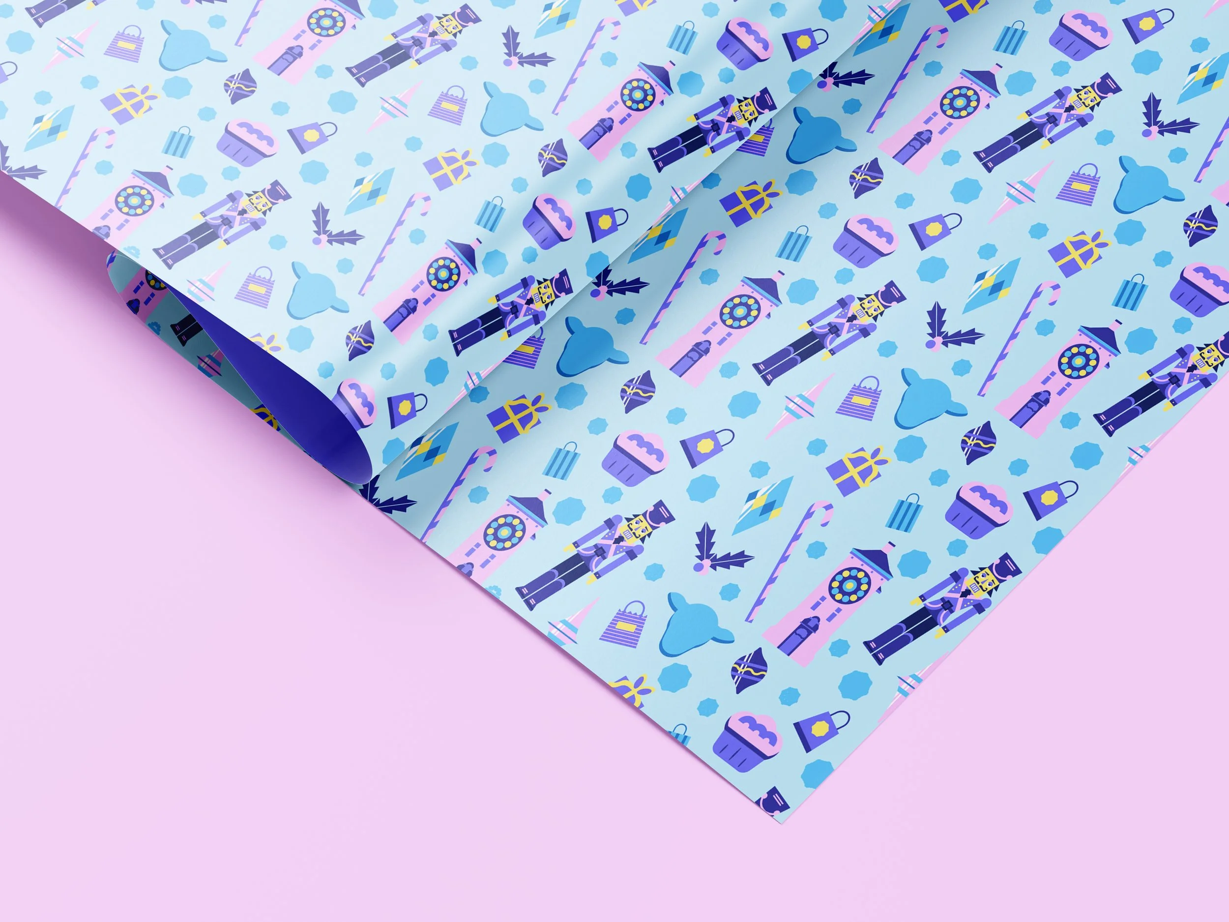 Colorful wrapping paper with Christmas-themed illustrations including nutcrackers, candy canes, ornaments, presents, Christmas hats, and mistletoe, laid over a pastel pink background.