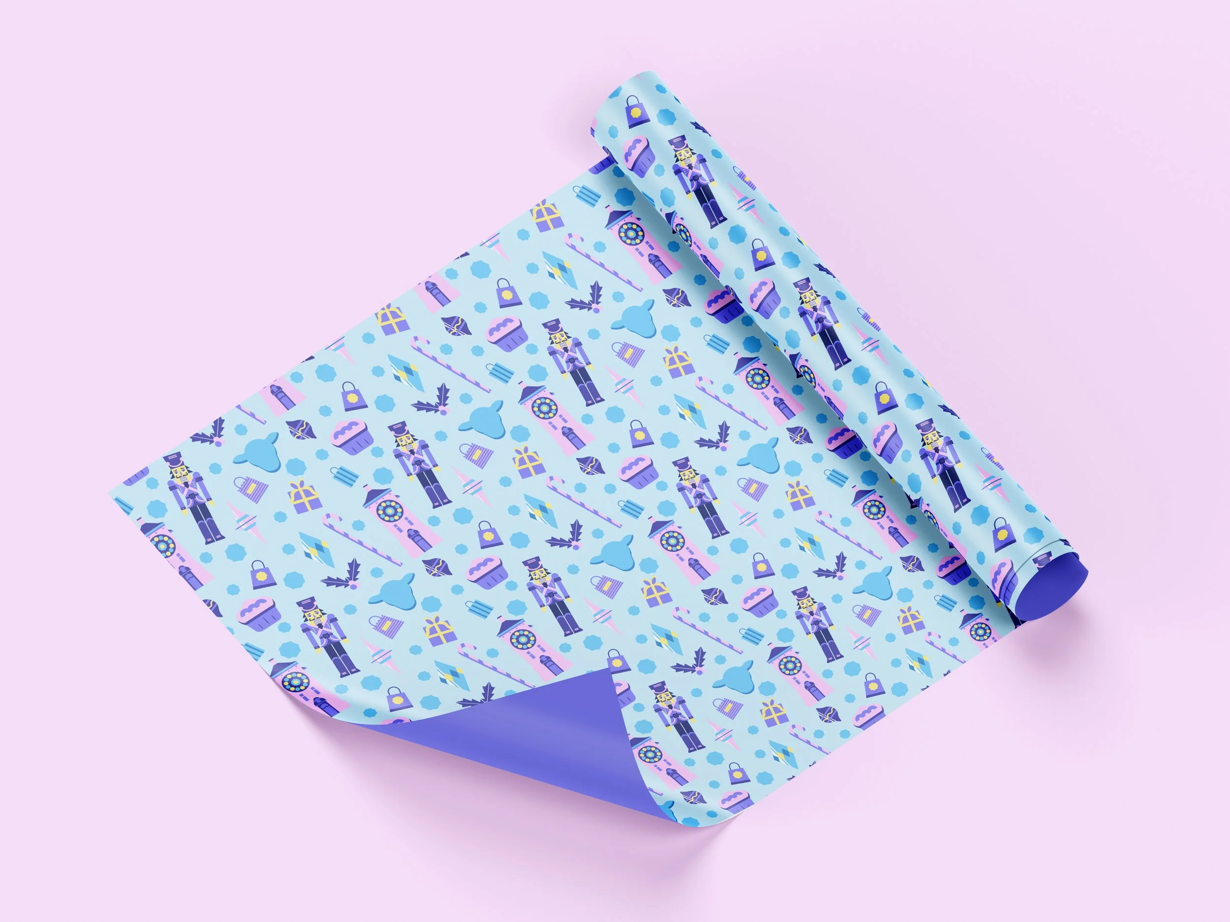 A roll of wrapping paper with a blue background, featuring pattern illustrations of gift boxes, crowns, sunglasses, and toy soldiers, partially unrolled on a pastel pink surface.