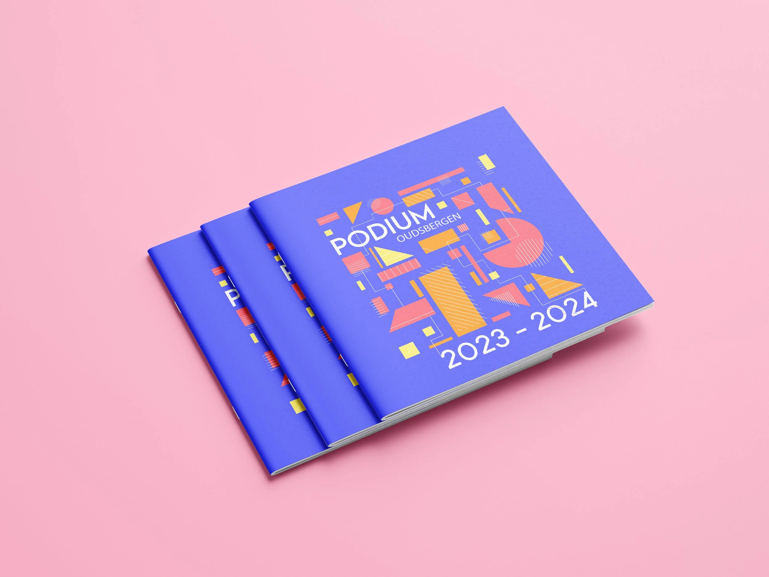 Three blue programs or brochures with colorful abstract geometric designs on a pink background, labeled 'Podium Oudbergen 2023-2024'.