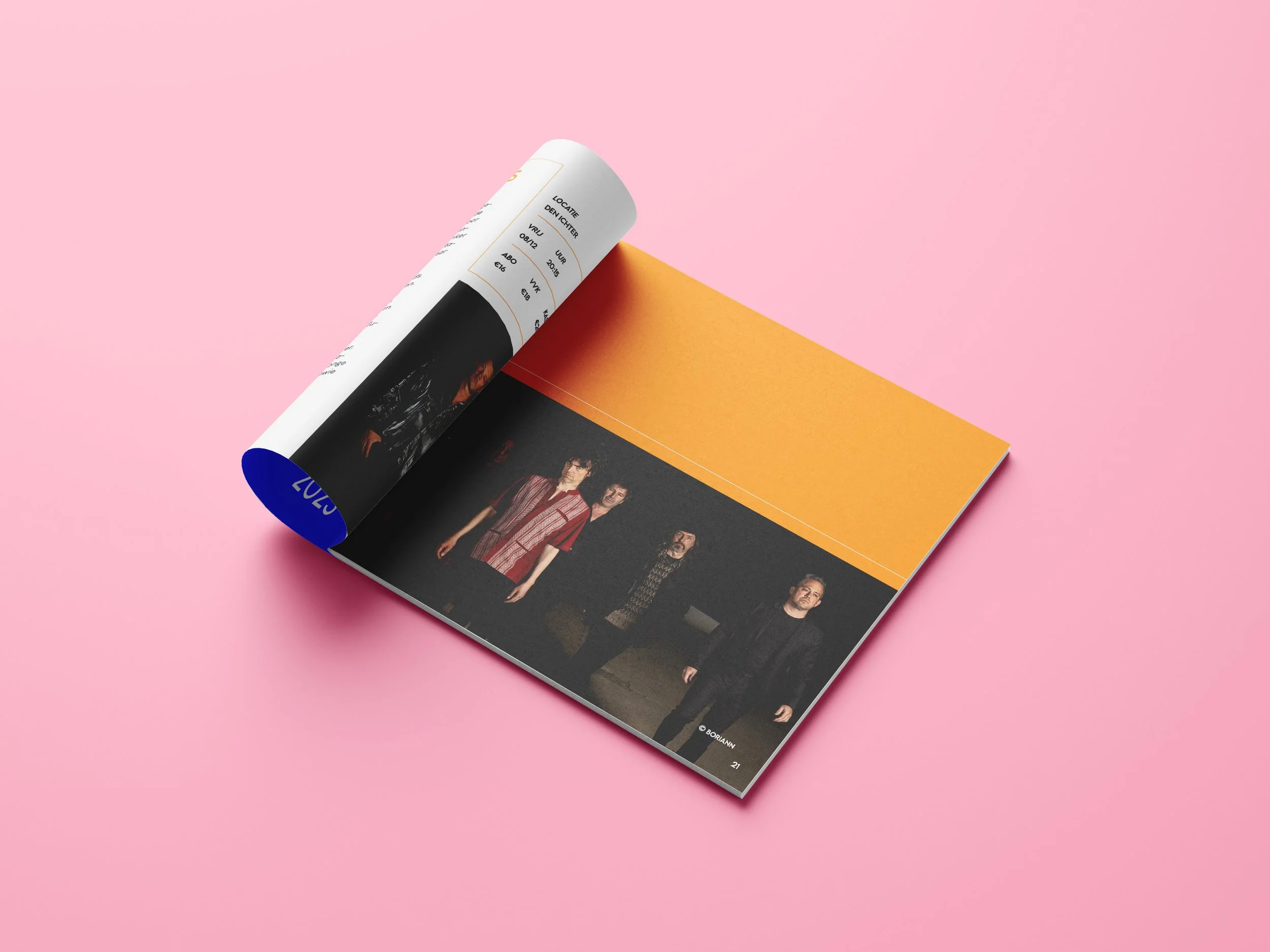 An open magazine on a pink surface showing a photograph of four men standing in a dark setting and a background with a yellow and orange gradient.