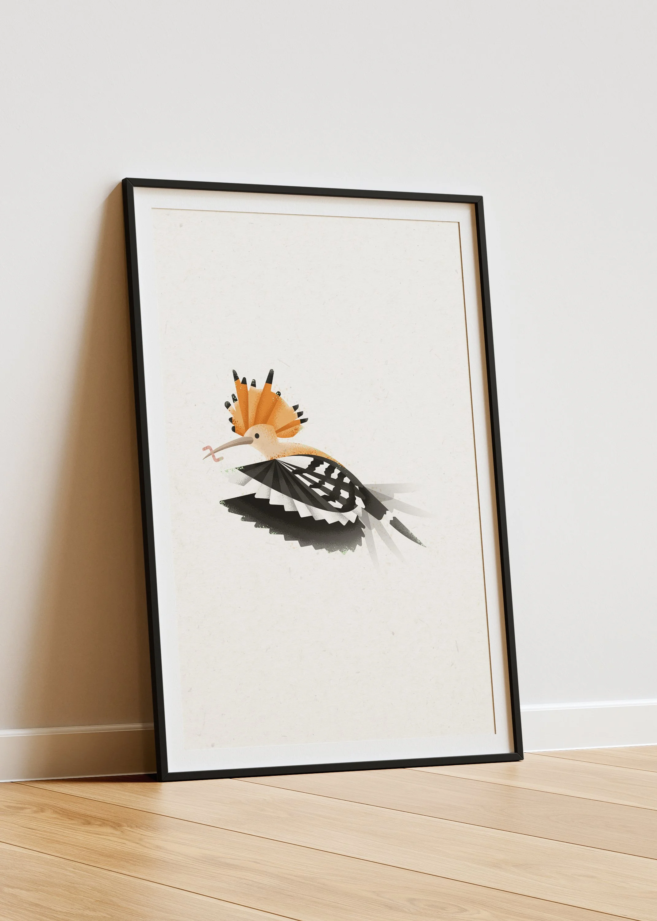 Framed art print of a stylized bird with orange crest, black and white wings and tail, displayed leaning against a white wall.