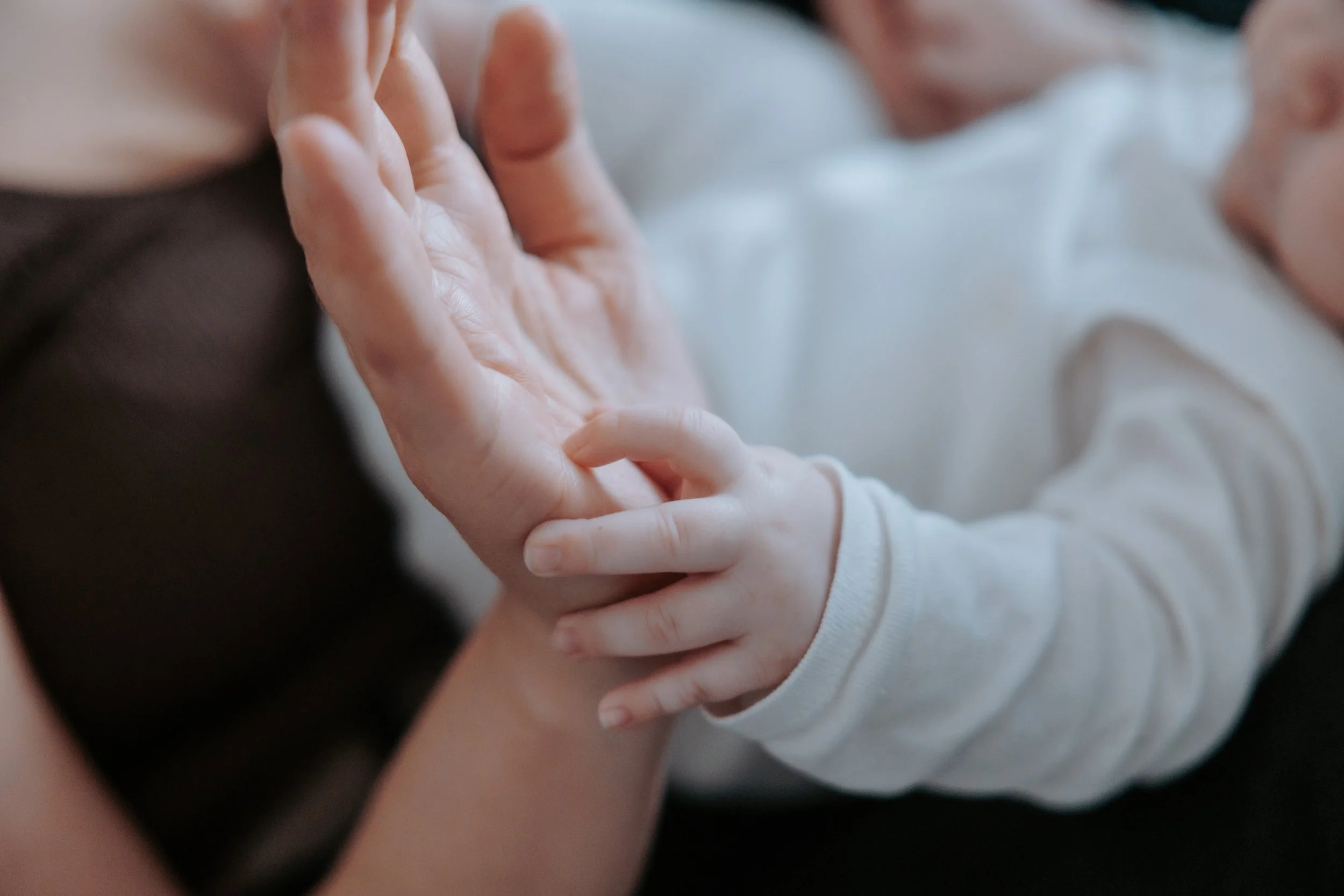 Photo d'une main de bébé contre celle de sa maman lors d'une séance photo à Paris