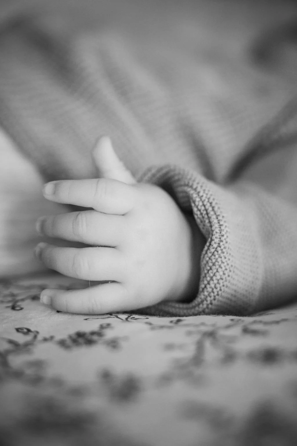 Main d'un bébé en noir et blanc, vêtue d'un pull en tricot.