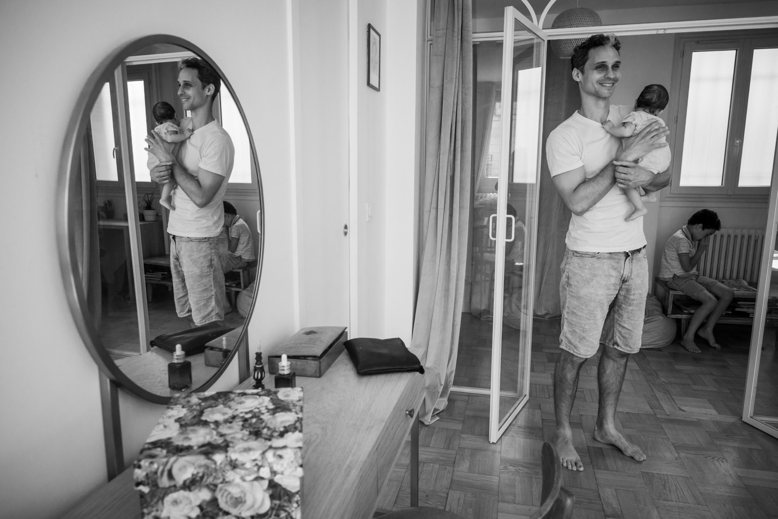 un papa tiens son nouveau né dans les bras lors d'une séance photo de famille à paris