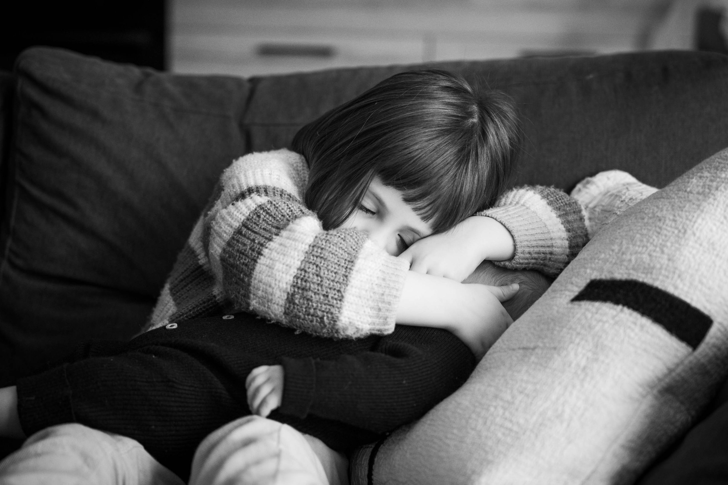 Enfant dormant sur un canapé avec un pull rayé.