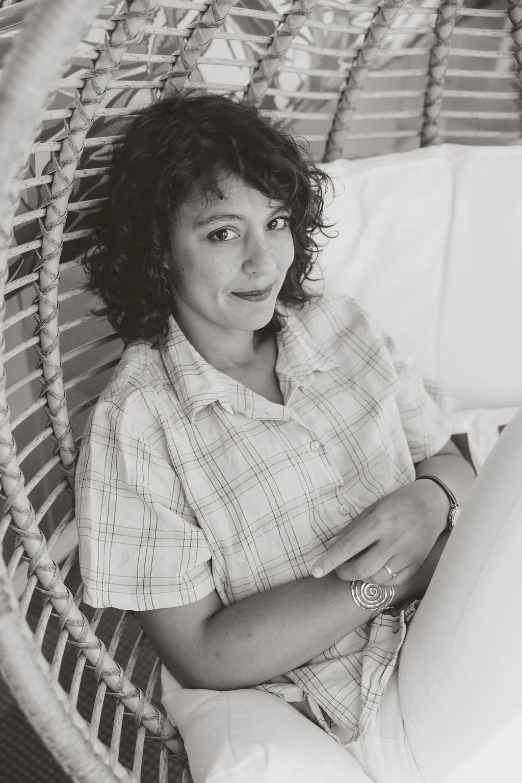 Jennifer buckle, photographe à paris est assise dans un siège en rotin et regarde l'appareil de la photographe Leslie