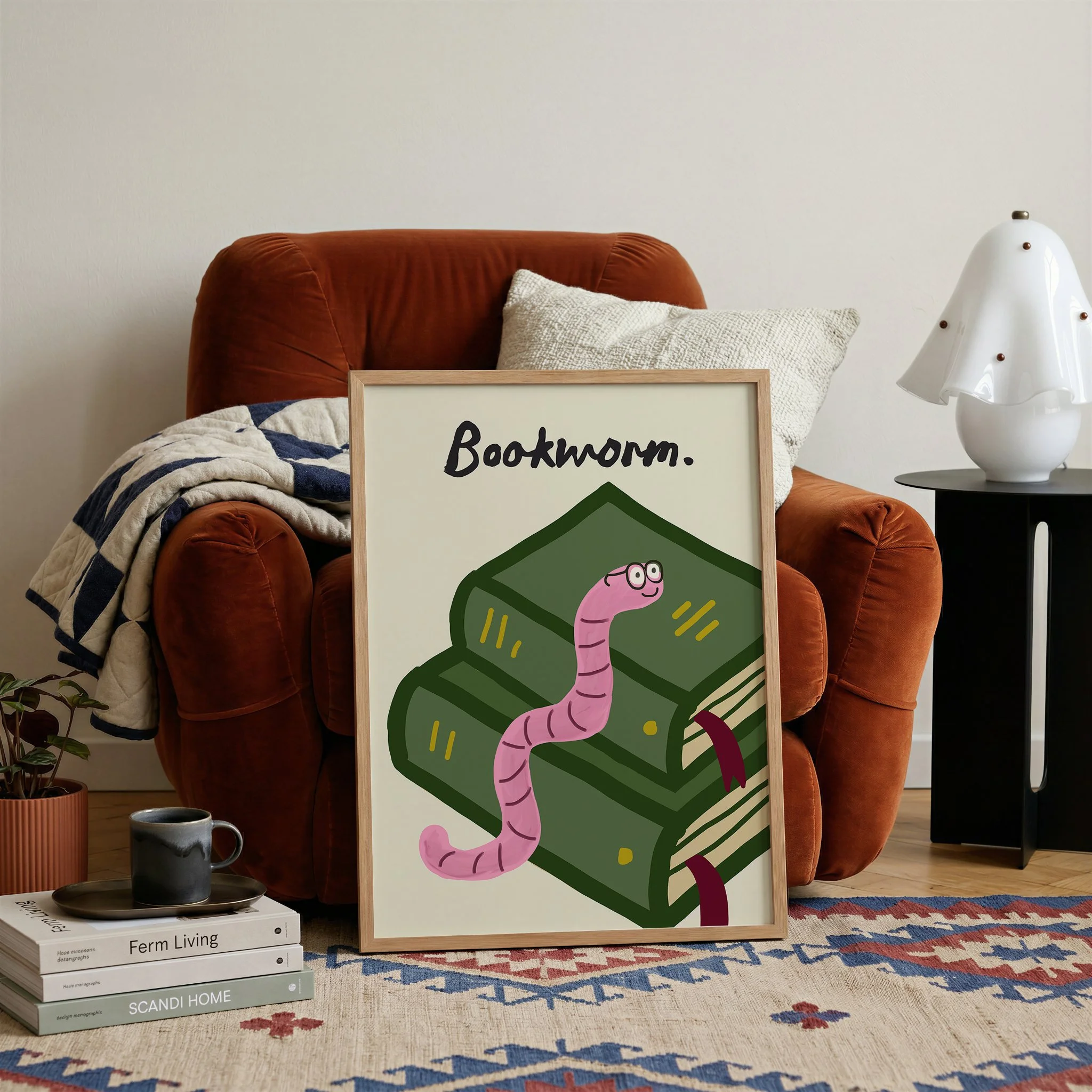 Bookworm art print featuring a pink illustrated worm on stacked green books with typography text, styled in a neutral modern living room
