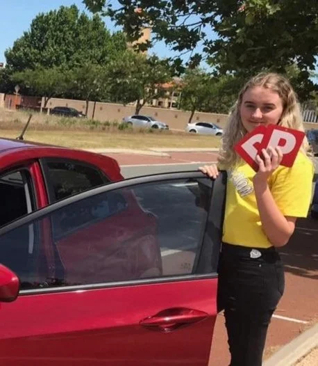 Victorious Driving School student Laurie holding their Red P plates after passing their PDA.
