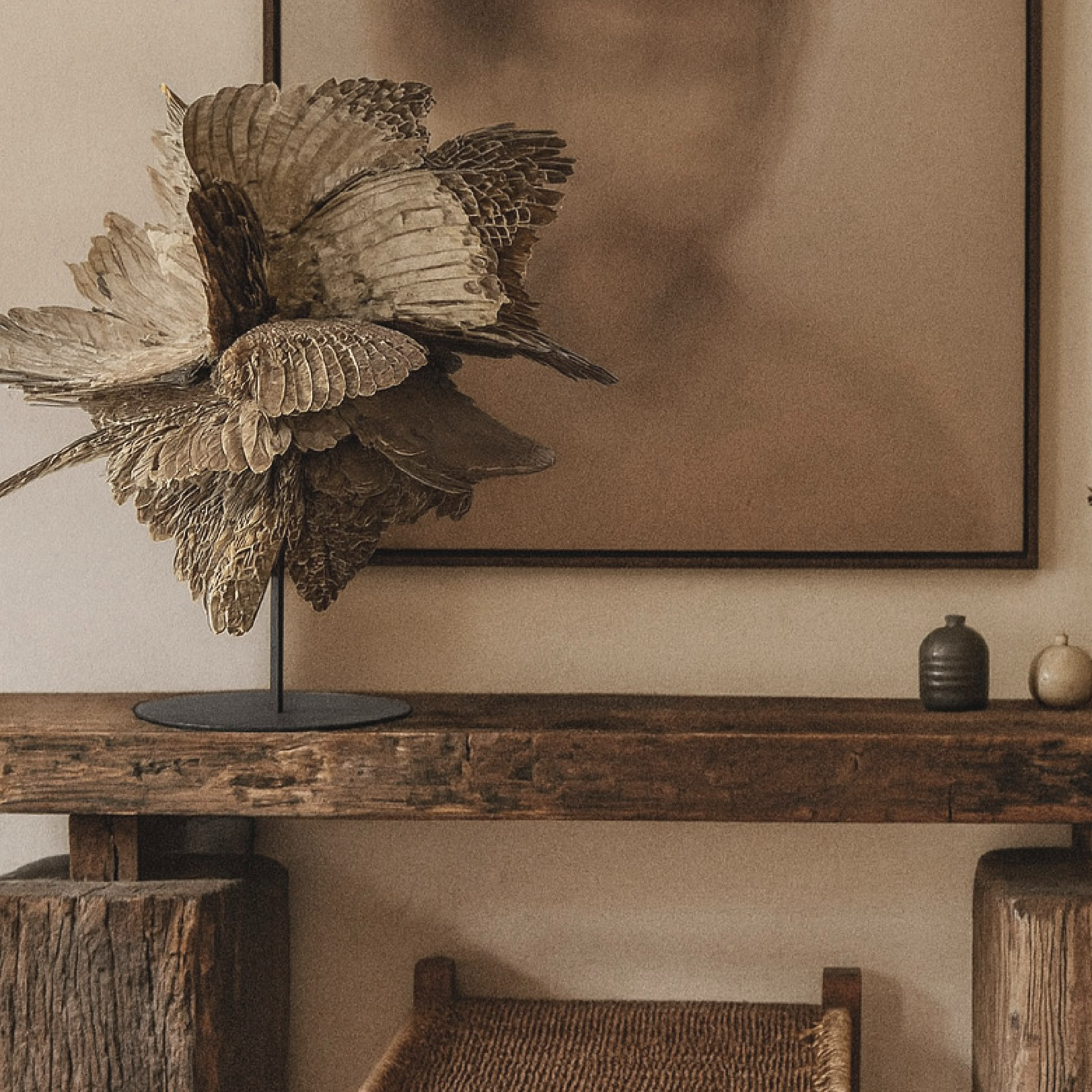 Decorative display featuring a sculpture of birds on a wooden table, with two small vases and a framed art piece on the wall in a neutral-toned room.