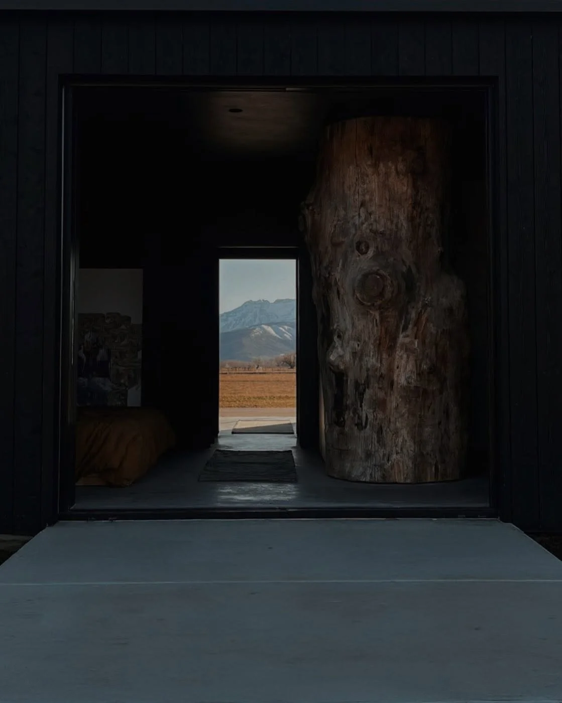 View through a dark interior doorway to mountains in the distance with a field in the foreground.