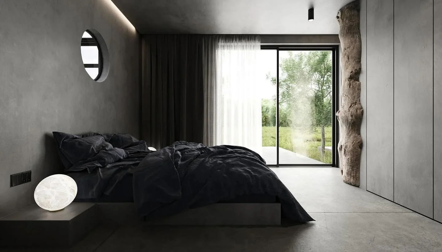 Modern bedroom with gray concrete walls, black bedding, a glowing orb bedside lamp, a round window, sheer curtains near large glass doors, and a wooden accent feature on the right wall overlooking greenery outside.
