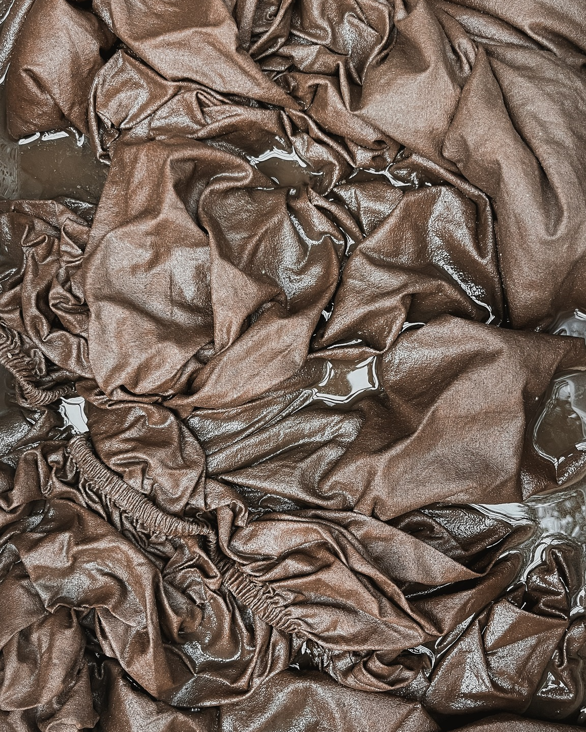 Close-up of crumpled brown fabric submerged in water.