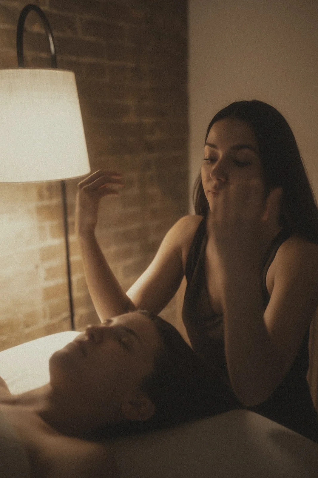 Dimly lit room with woman performing gentle facial massage on relaxed client, demonstrating benefits of facial massage.