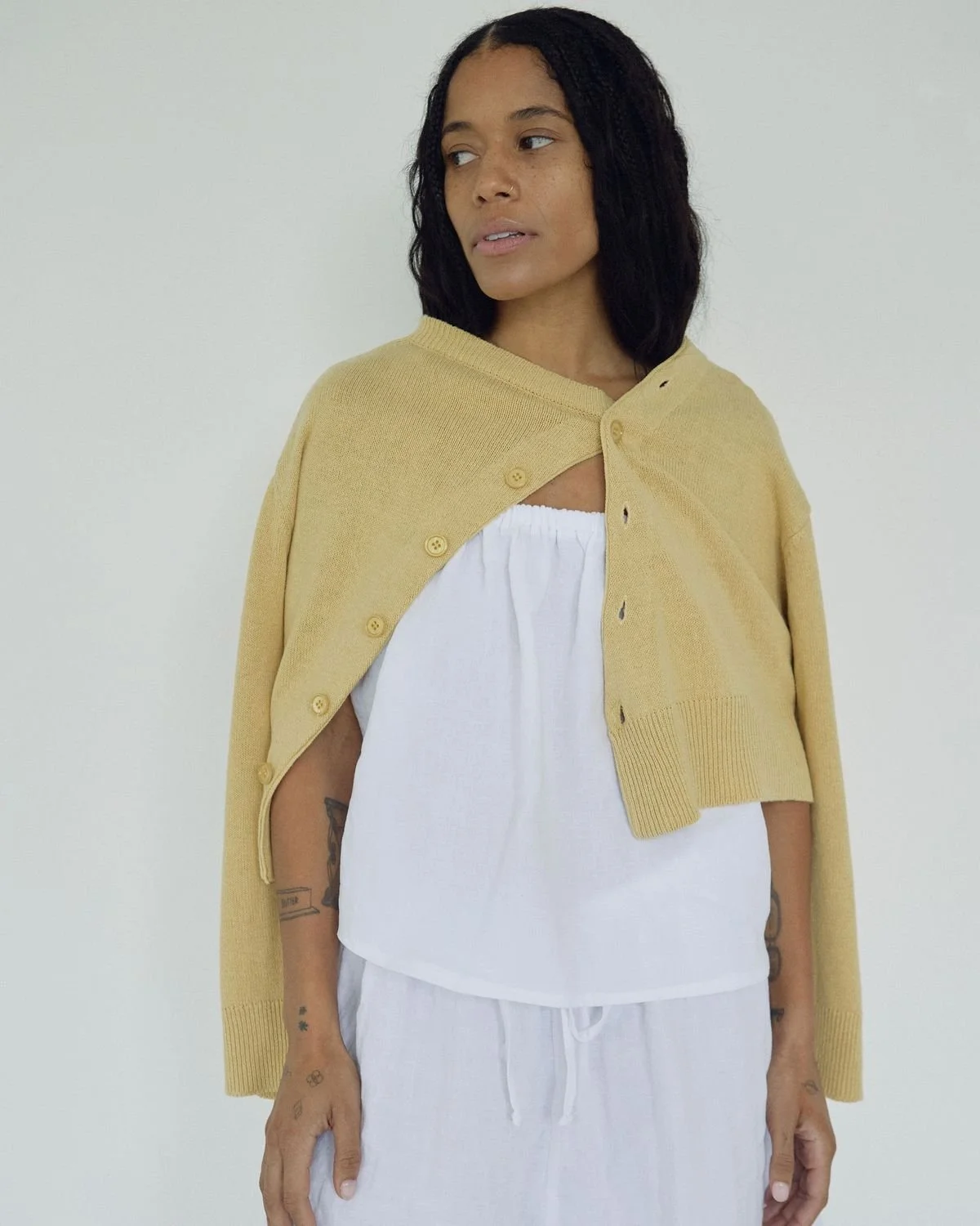 Stylish model in Bohème Goods The Asymmetric Knit cardigan with wide sleeves, paired with white blouse and drawstring pants.