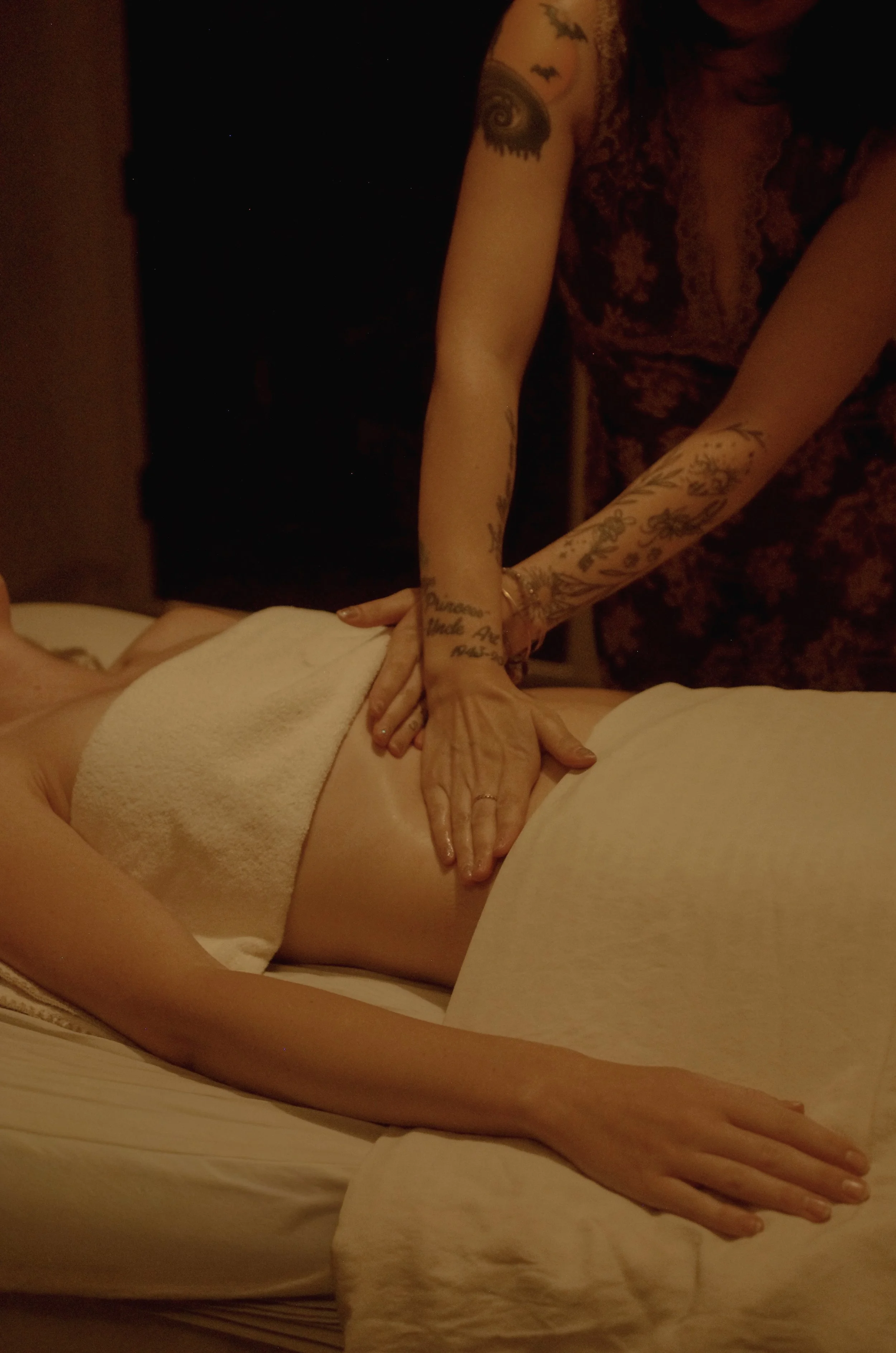 Aesthetician doing Brazilian Lymphatic Drainage to client's midsection on spa bed.