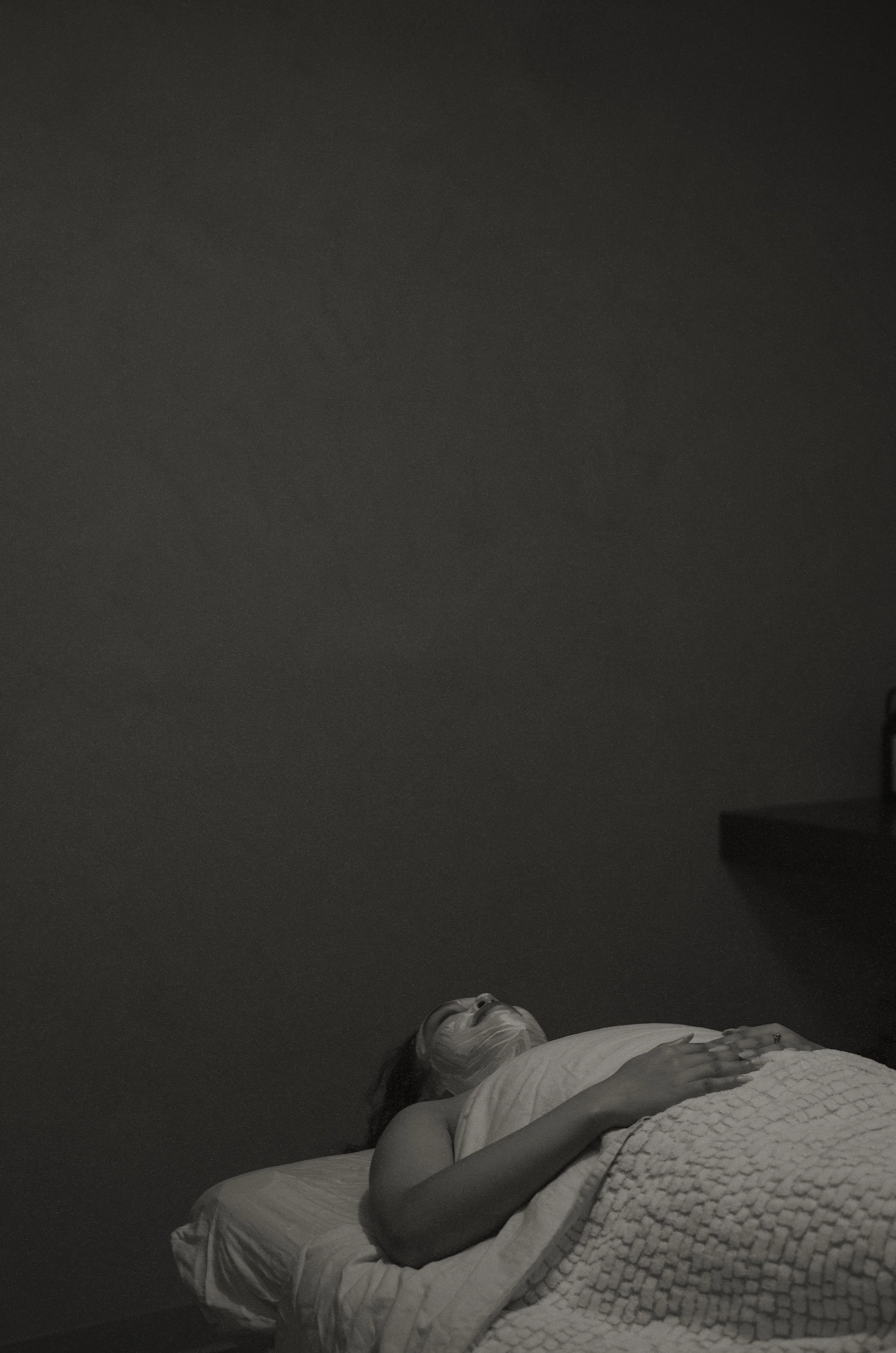Relaxed woman on spa bed during Brightening Facial Lacombe, wearing white face mask, eyes closed under cozy blanket.