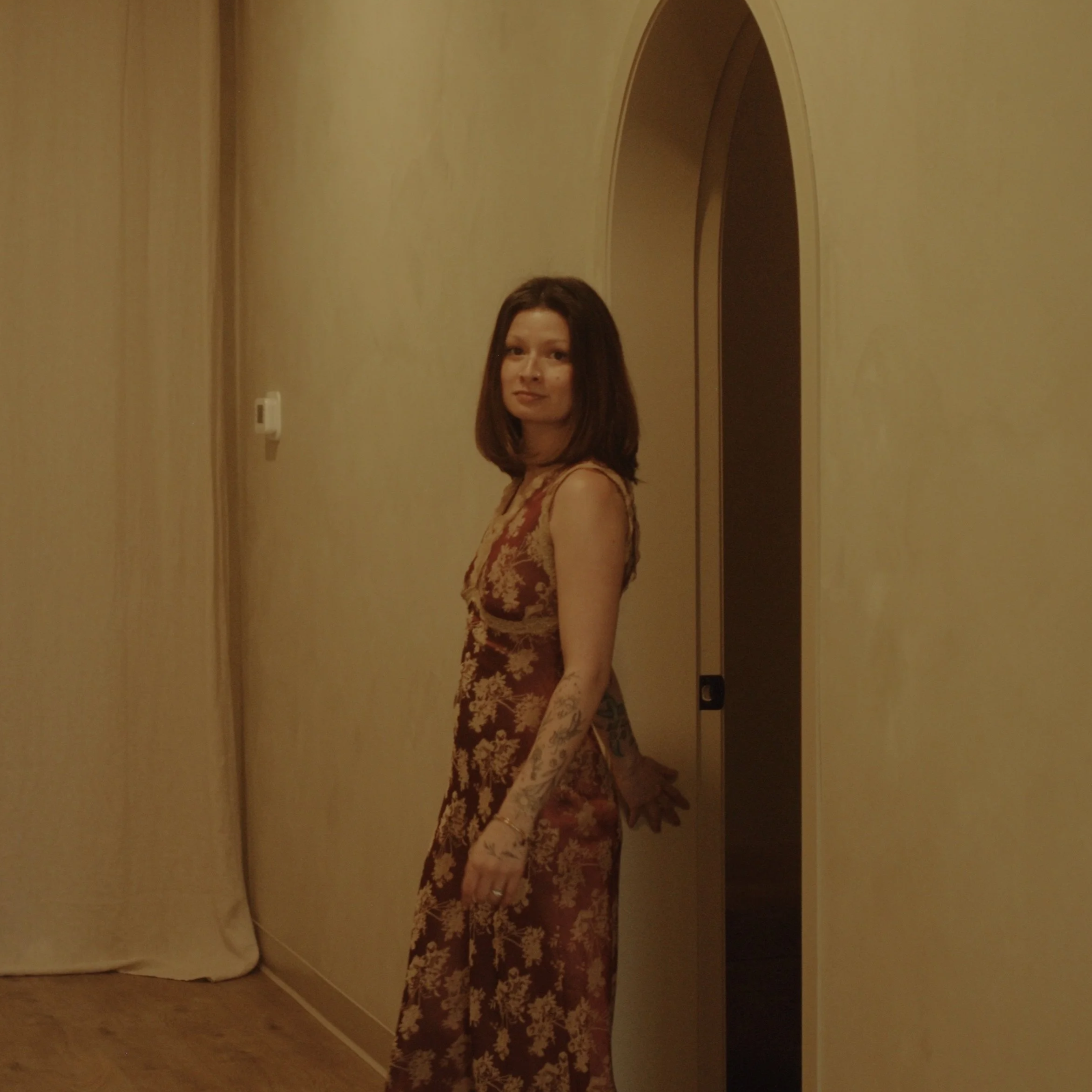 Lymphatic drainage expert Jamecia walks out of arched spa door in burgundy floral dress downtown Lacombe