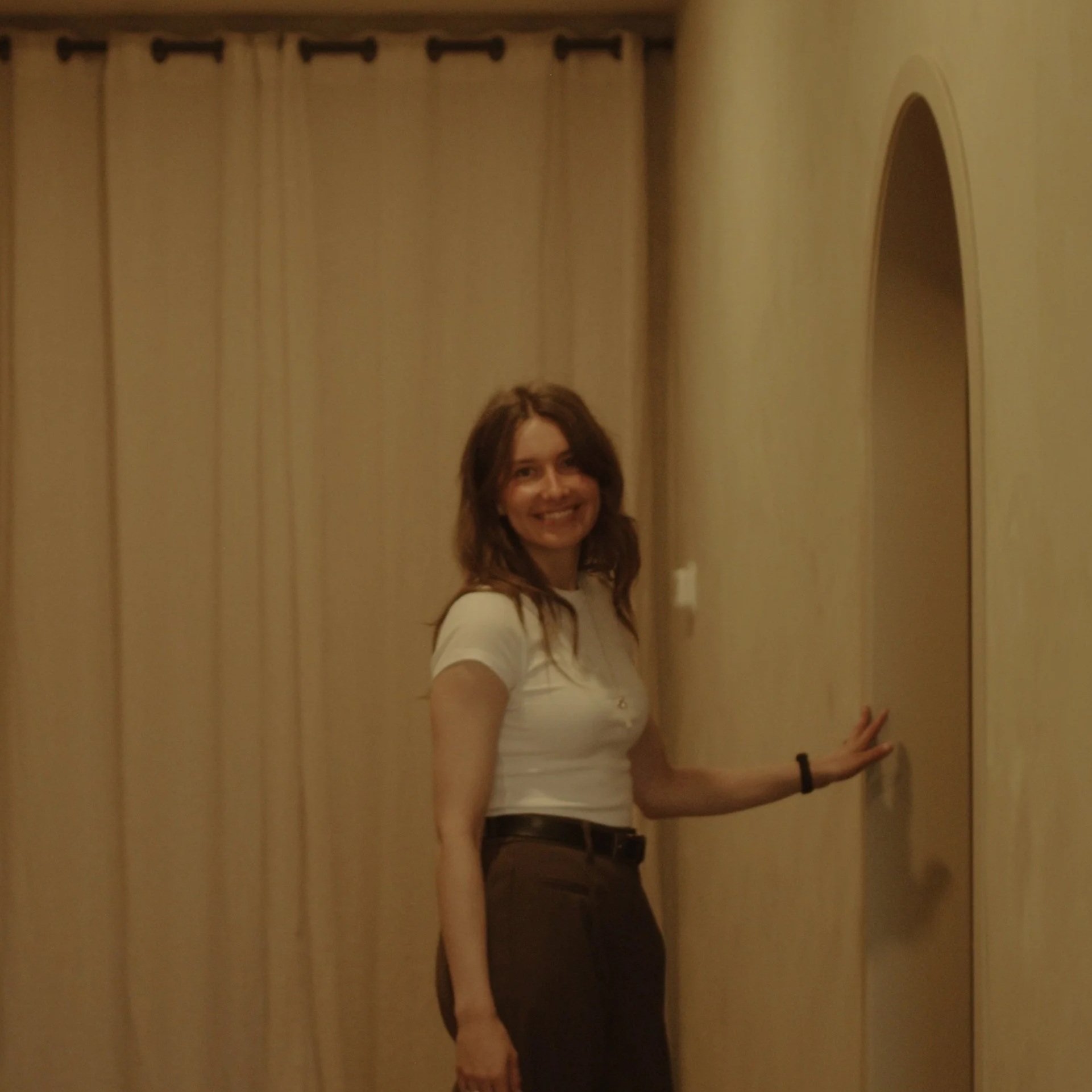 Reiki practitioner Christeen has her hand up against a rounded door frame while smiling at camera downtown lacombe