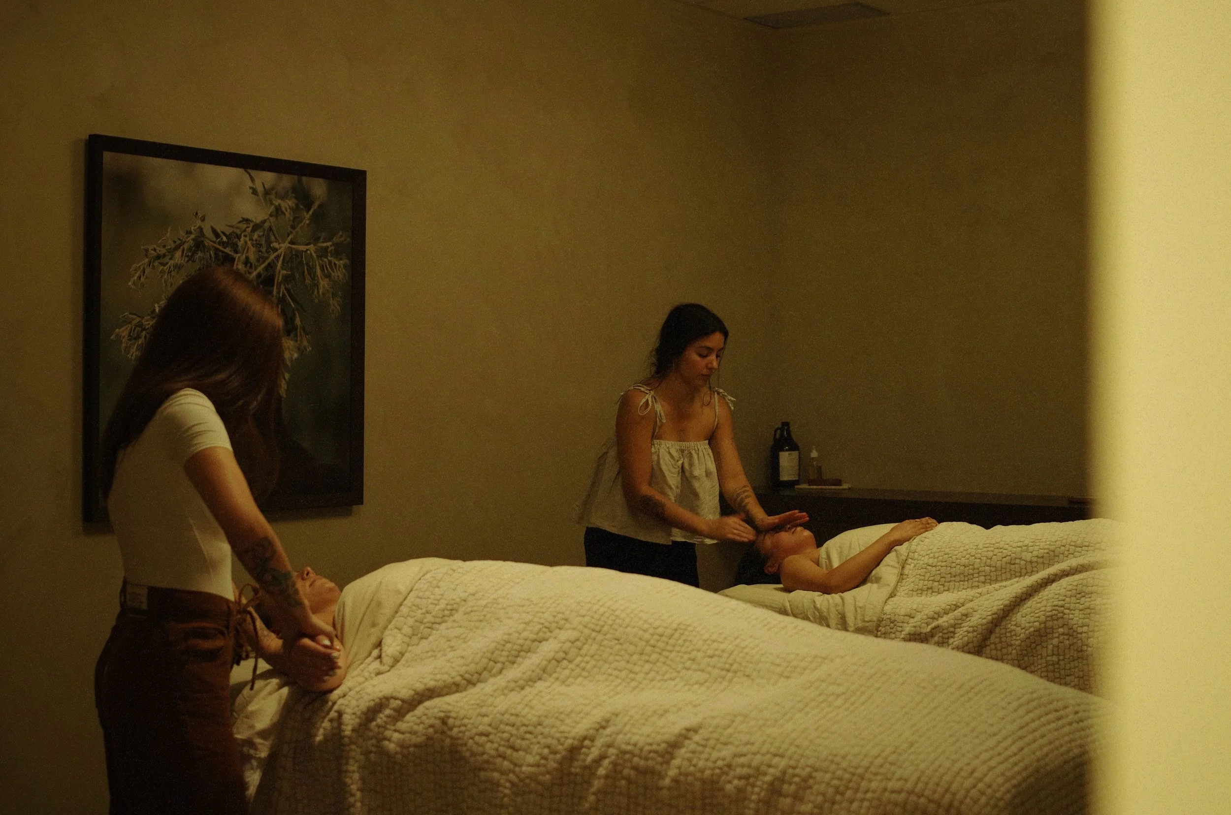 Therapist Sabrina applies Facial Massage Technique to client's face on spa table in dimly lit room.