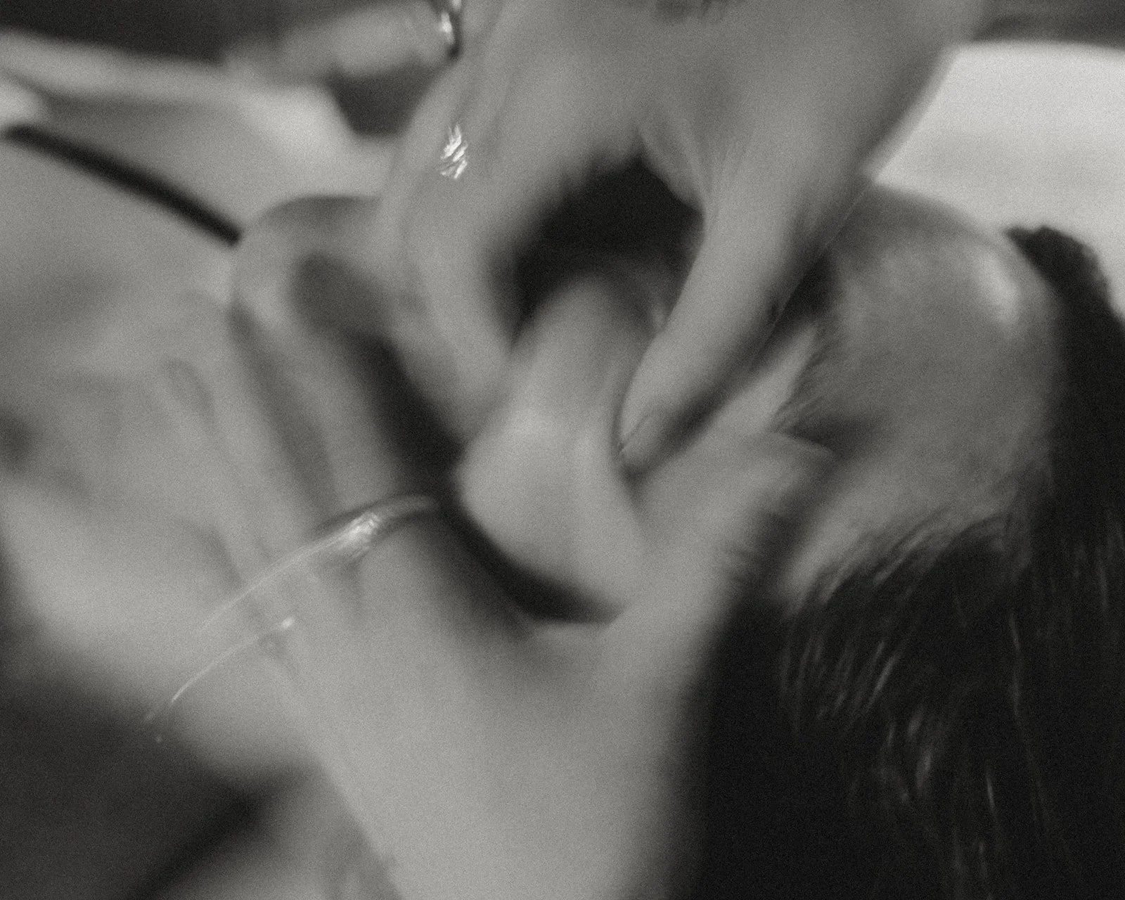 Blurred-motion black-and-white image of hand applying facial massage to jawline at home, demonstrating benefits of facial massage.
