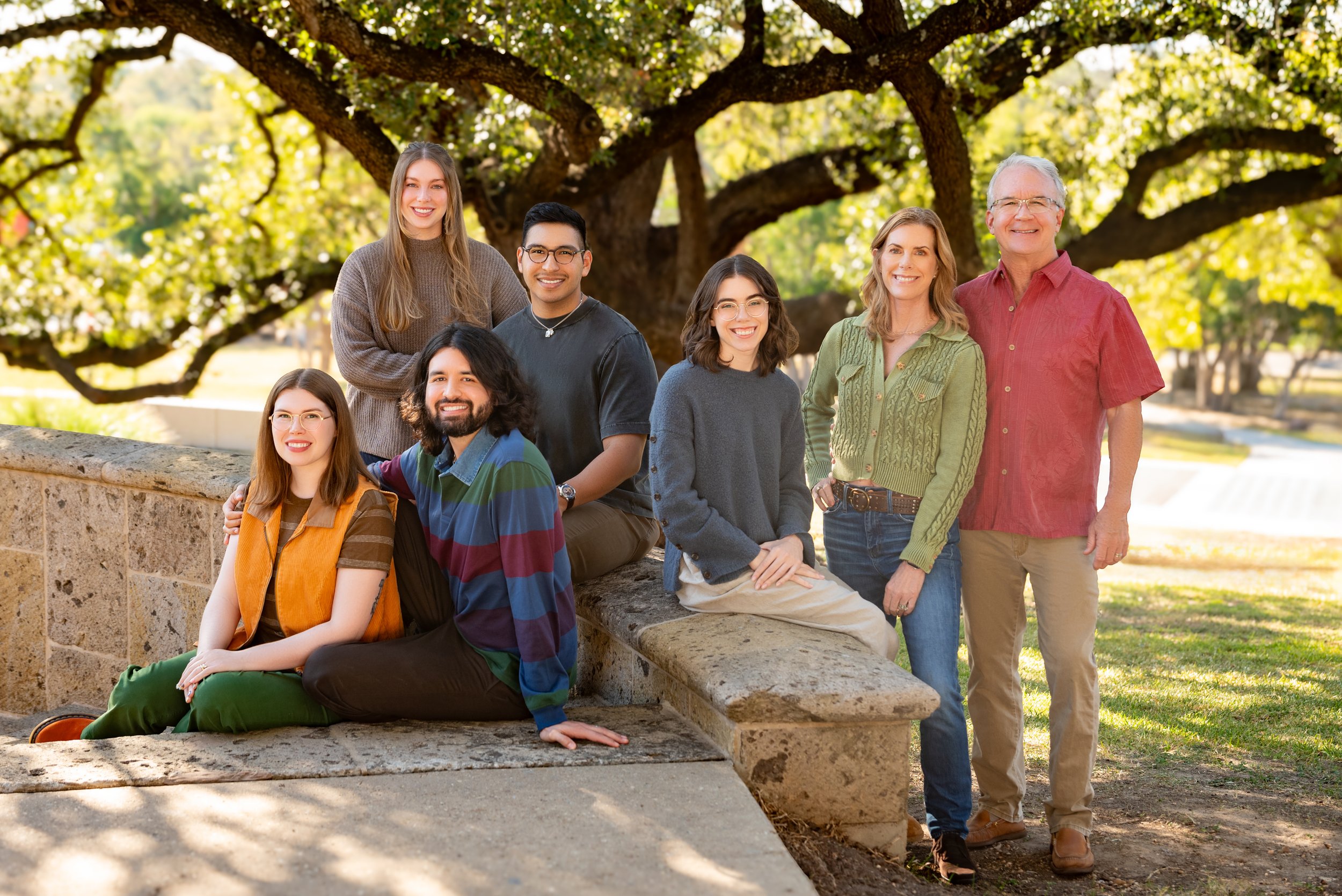 Extended family group wearing coordinated outfits.  They are posed in front of a tree at the McNay Art Museum
