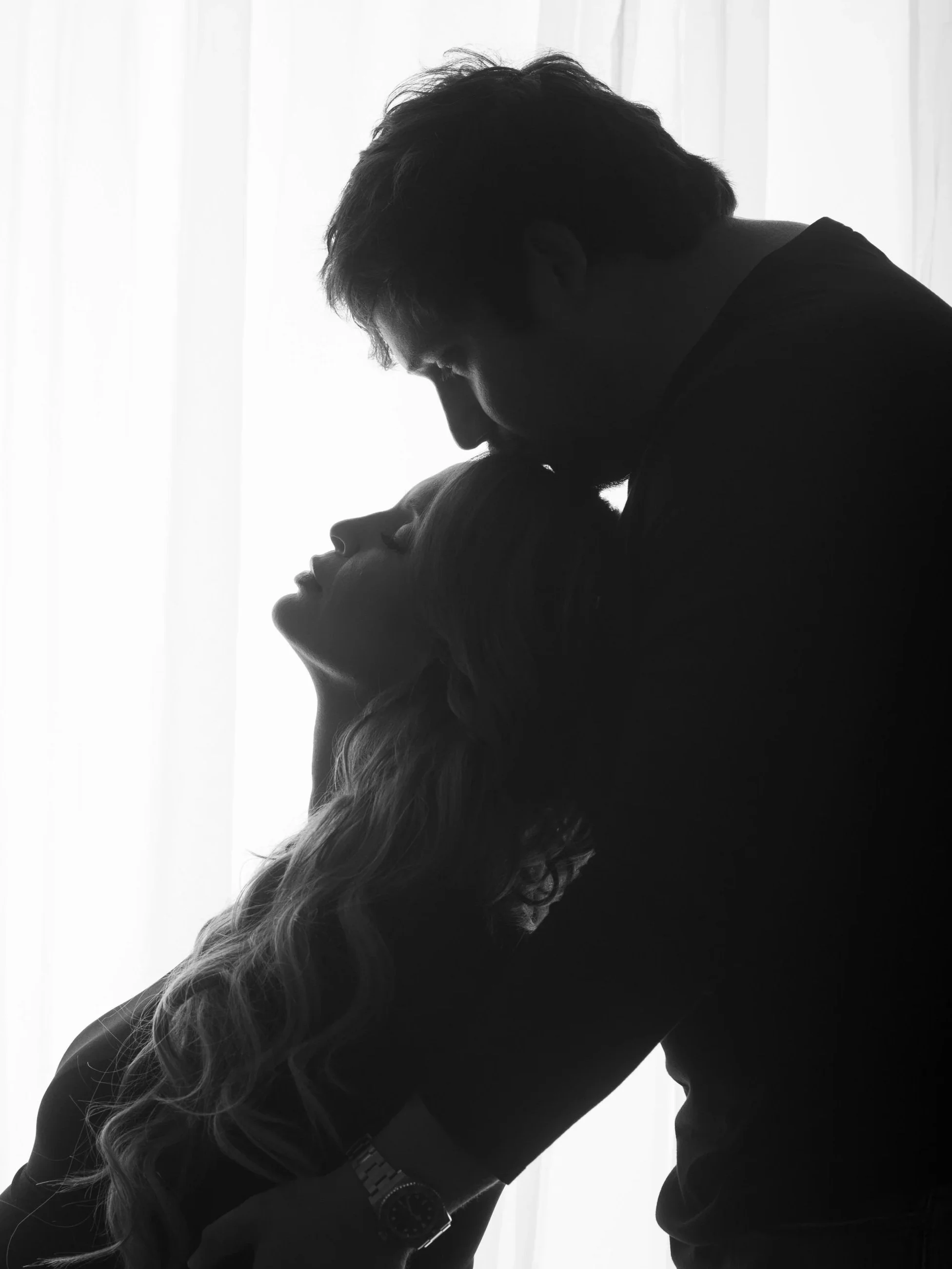 Husband kisses pregnant wife’s forehead during candid moment in San Antonio maternity session.