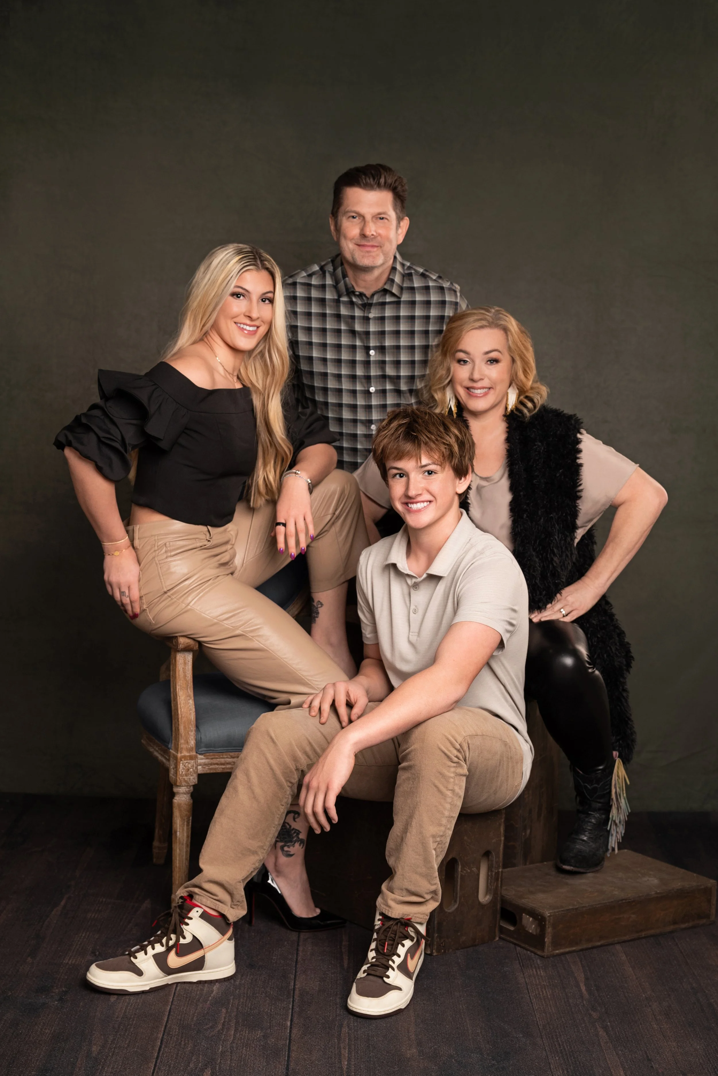 Husband and wife realtor team smiling together in a modern kitchen, with the woman leaning on the island in a red and white striped blouse and the man standing beside her in a blue blazer during a branding photo session in San Antonio