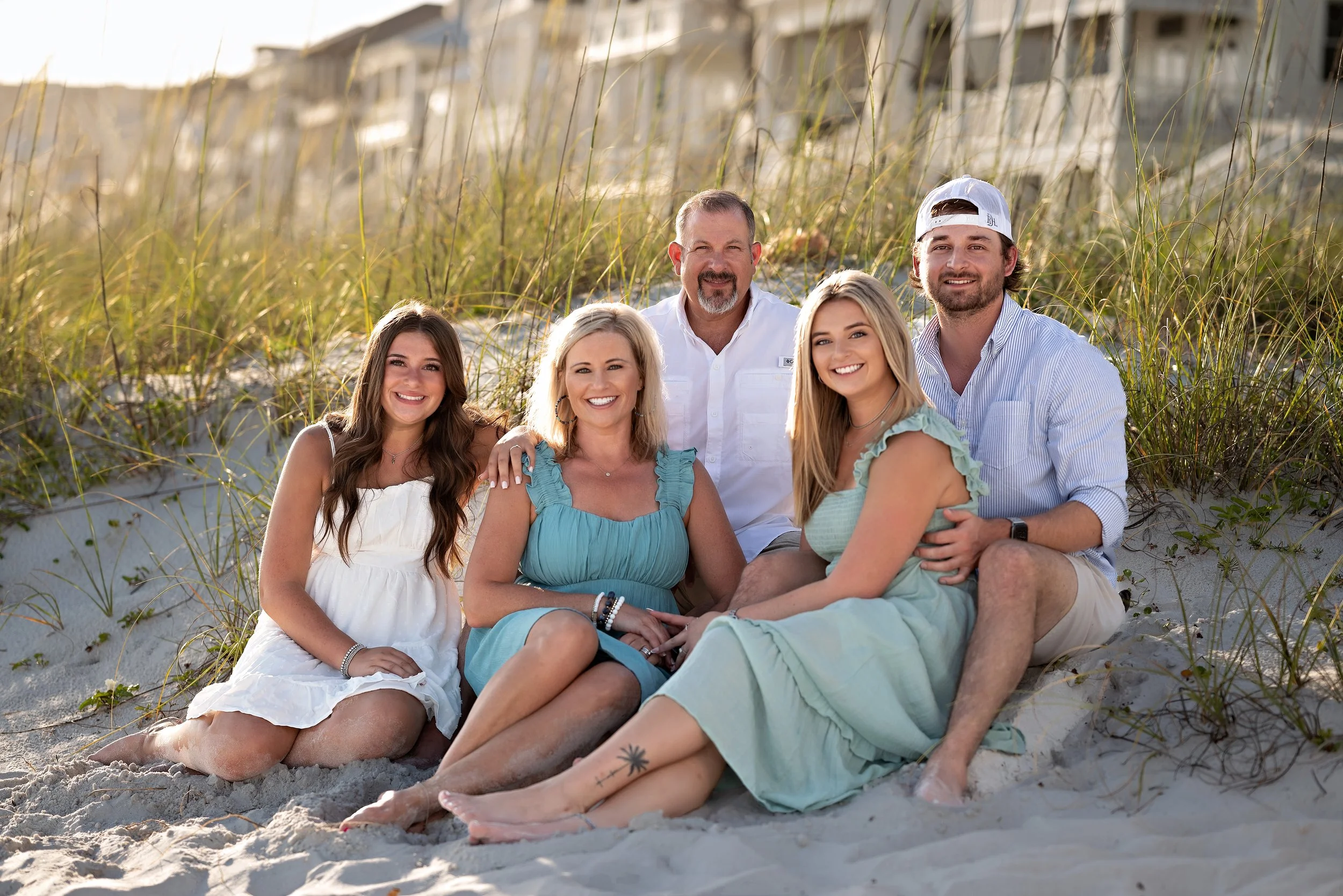 A relaxed family portrait sitting on the dunes of a Florida beach.