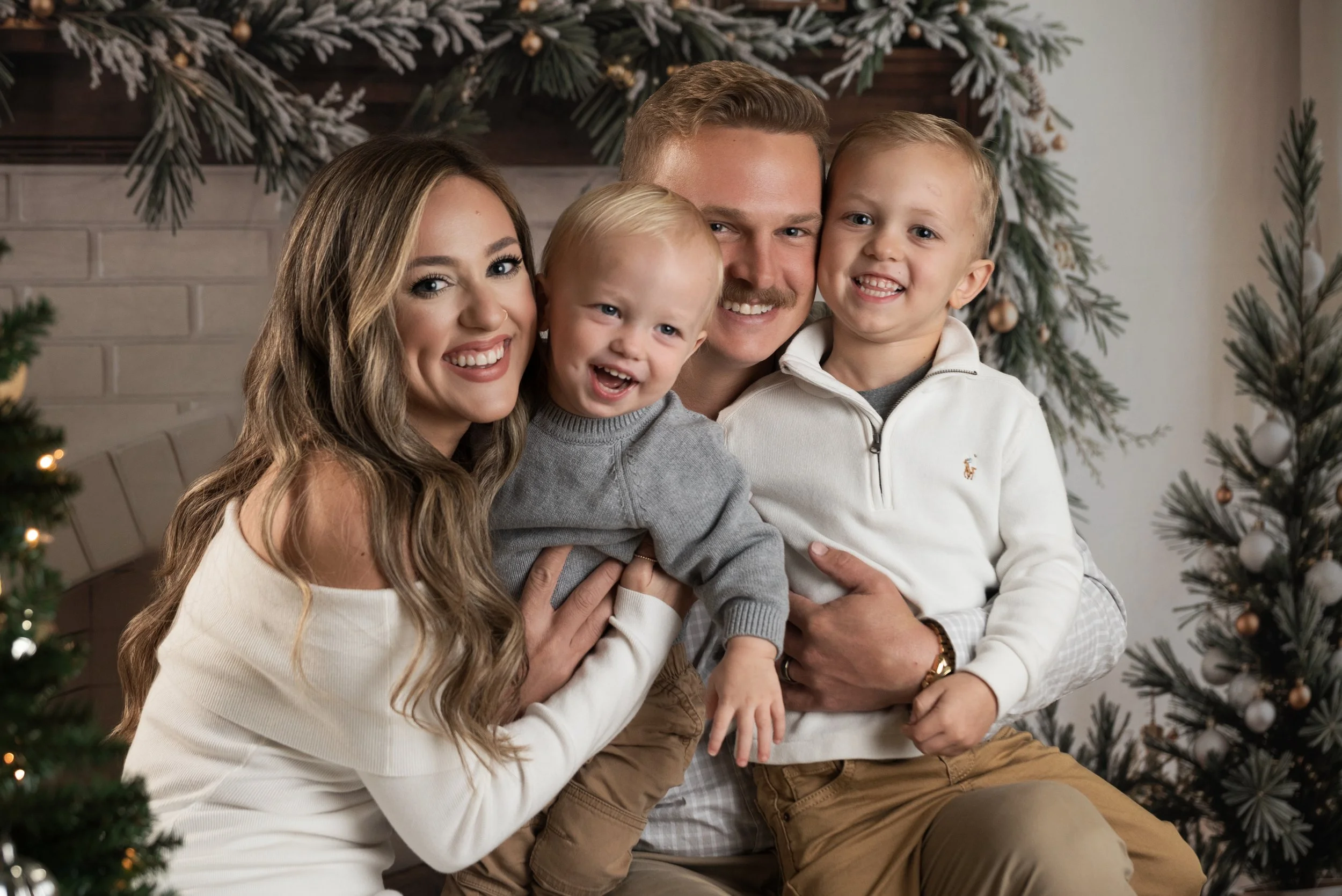 Laughing family with parents holding their boys for a holiday portrait.