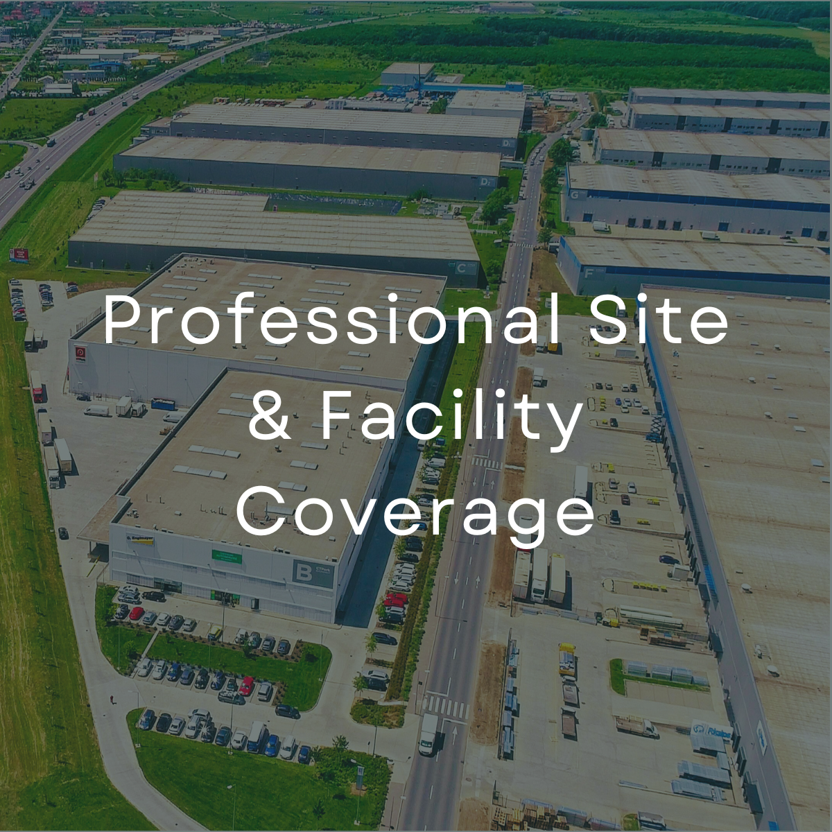 Aerial view of a large industrial complex with multiple warehouses, parking lots, and roads, surrounded by greenery.