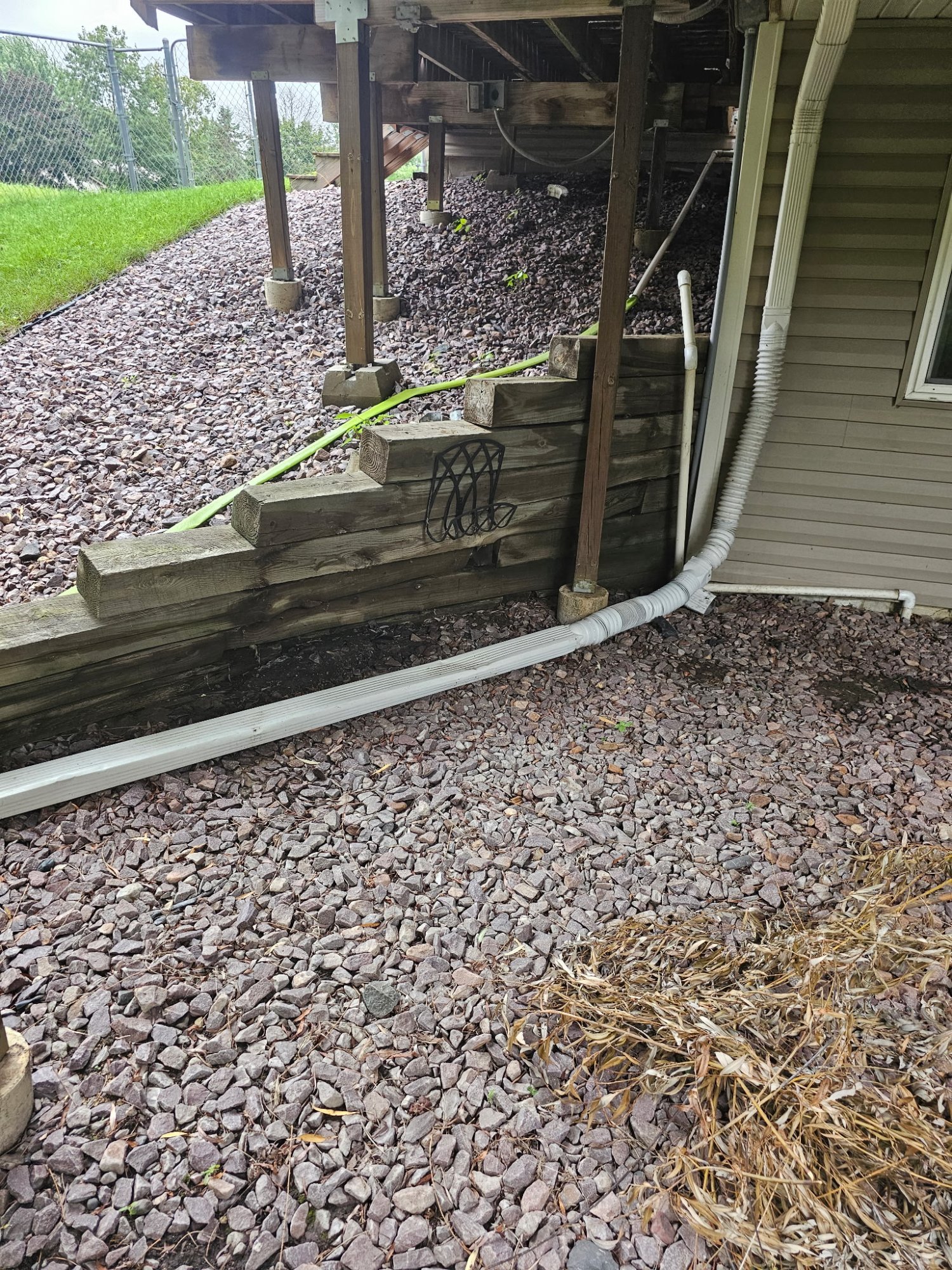 Rotted railroad tie wall pushing against second-story deck posts in Centerville MN — Heritage Outdoors before photo
